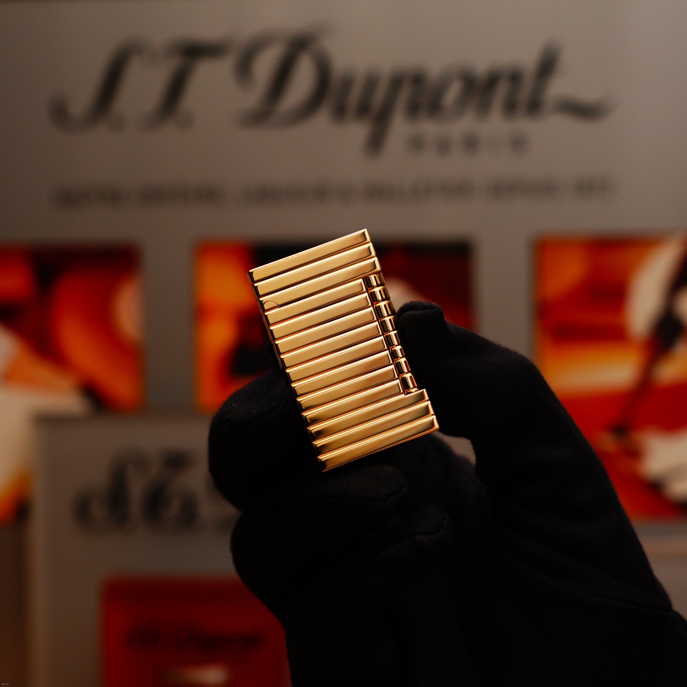 A gloved hand holds the ultra rare Vintage 1970 ST Dupont Lighter—Solid 18K Gold Masterpiece by Lucy Lighter, showcased in front of a blurred display to highlight its timeless elegance and masterful craftsmanship.