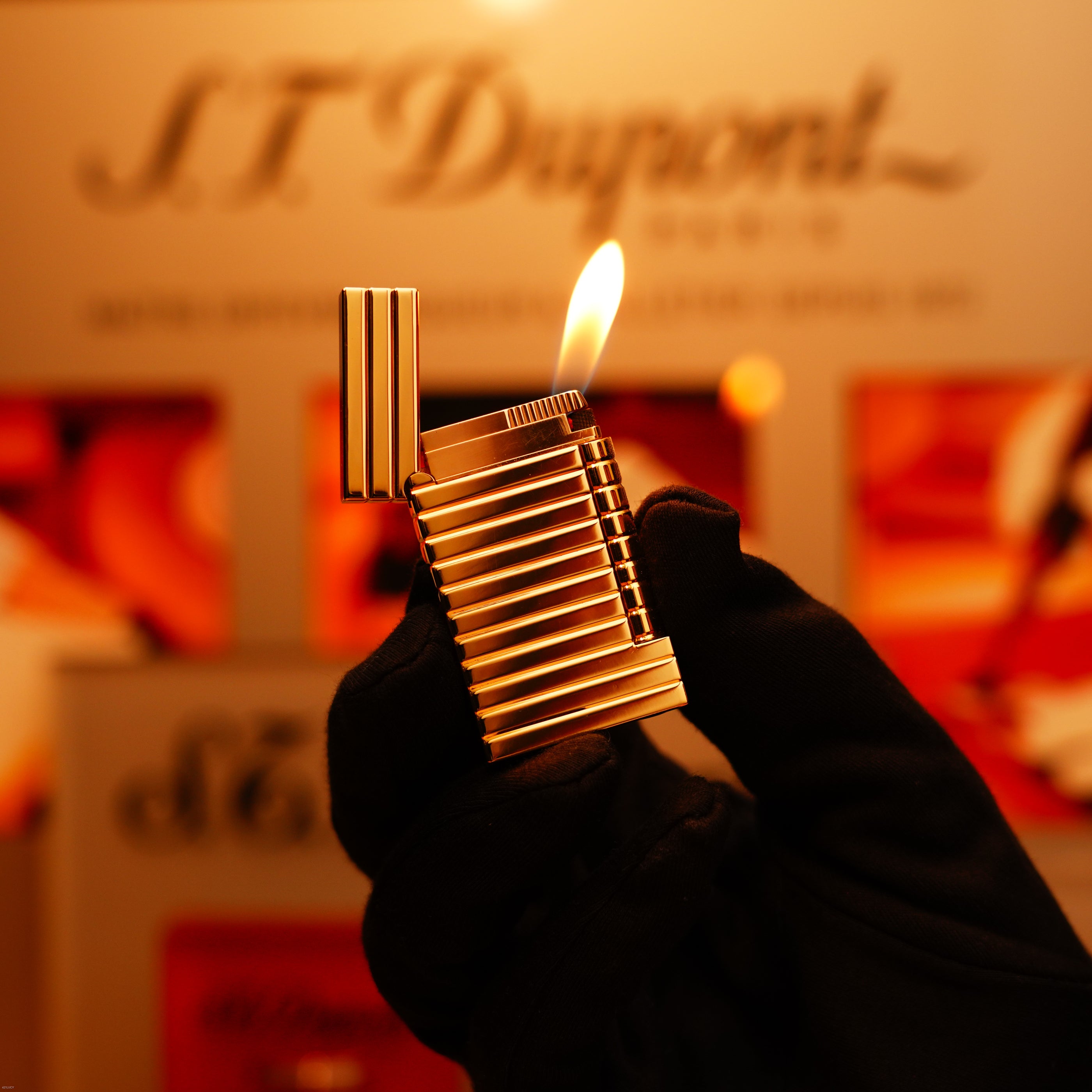 A gloved hand holds the Vintage 1970 Ultra Rare 1/1 ST Dupont Lighter in solid 18K gold by Lucy Lighter, with a blurred branded background.