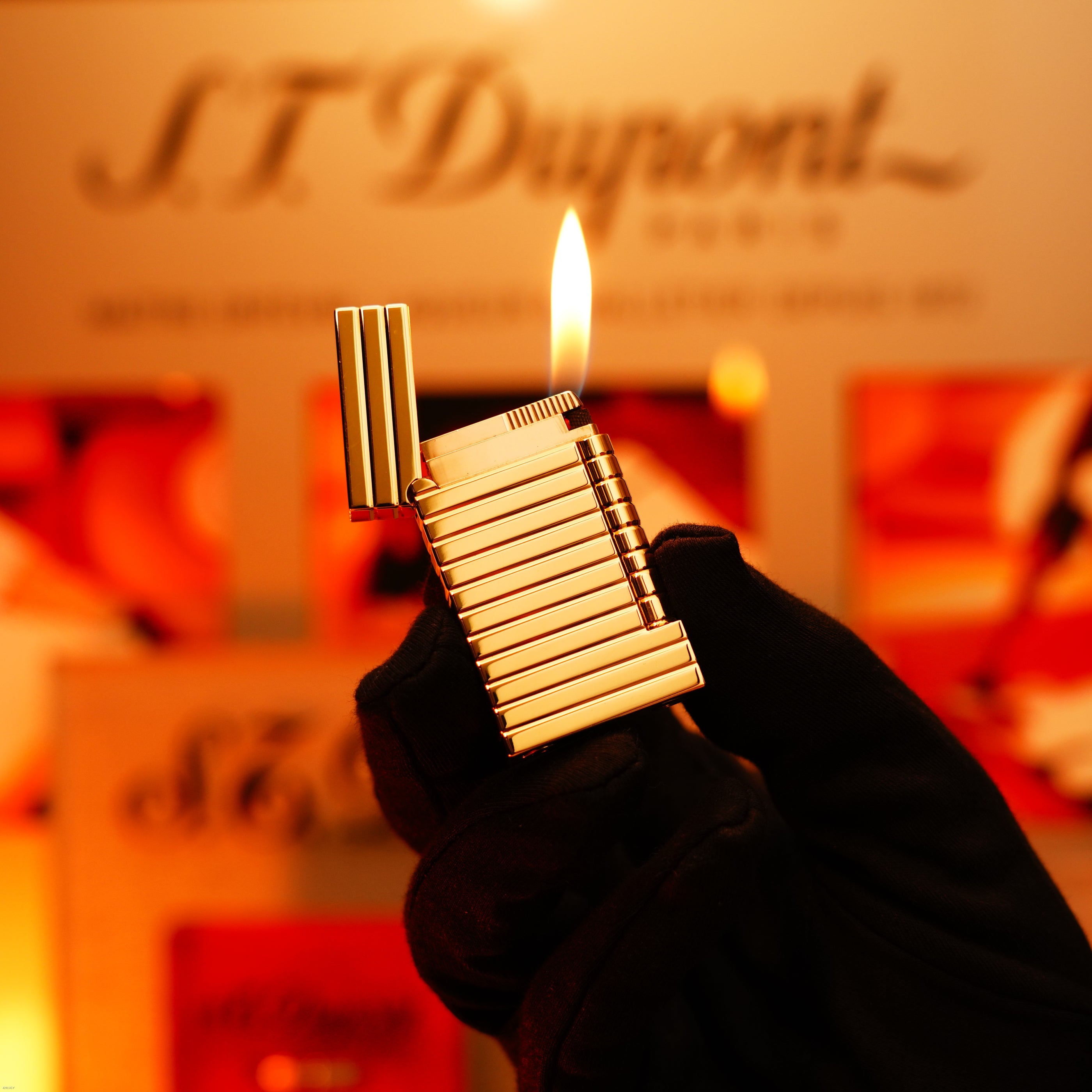 A gloved hand holds the ultra-rare Vintage 1970 ST Dupont Lighter—Solid 18K Gold Masterpiece by Lucy Lighter—lit with its lid open, against a blurred branded background.