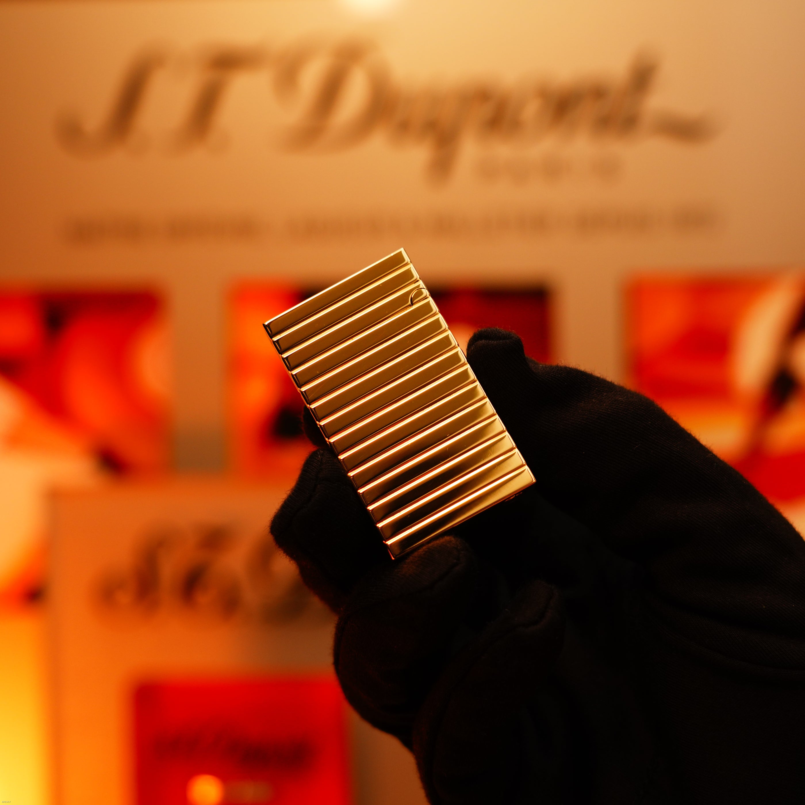 A gloved hand holds a Vintage 1970 Ultra Rare 1/1 ST Dupont Lighter – Solid 18K Gold Masterpiece by Lucy Lighter; blurred branding appears in the background.