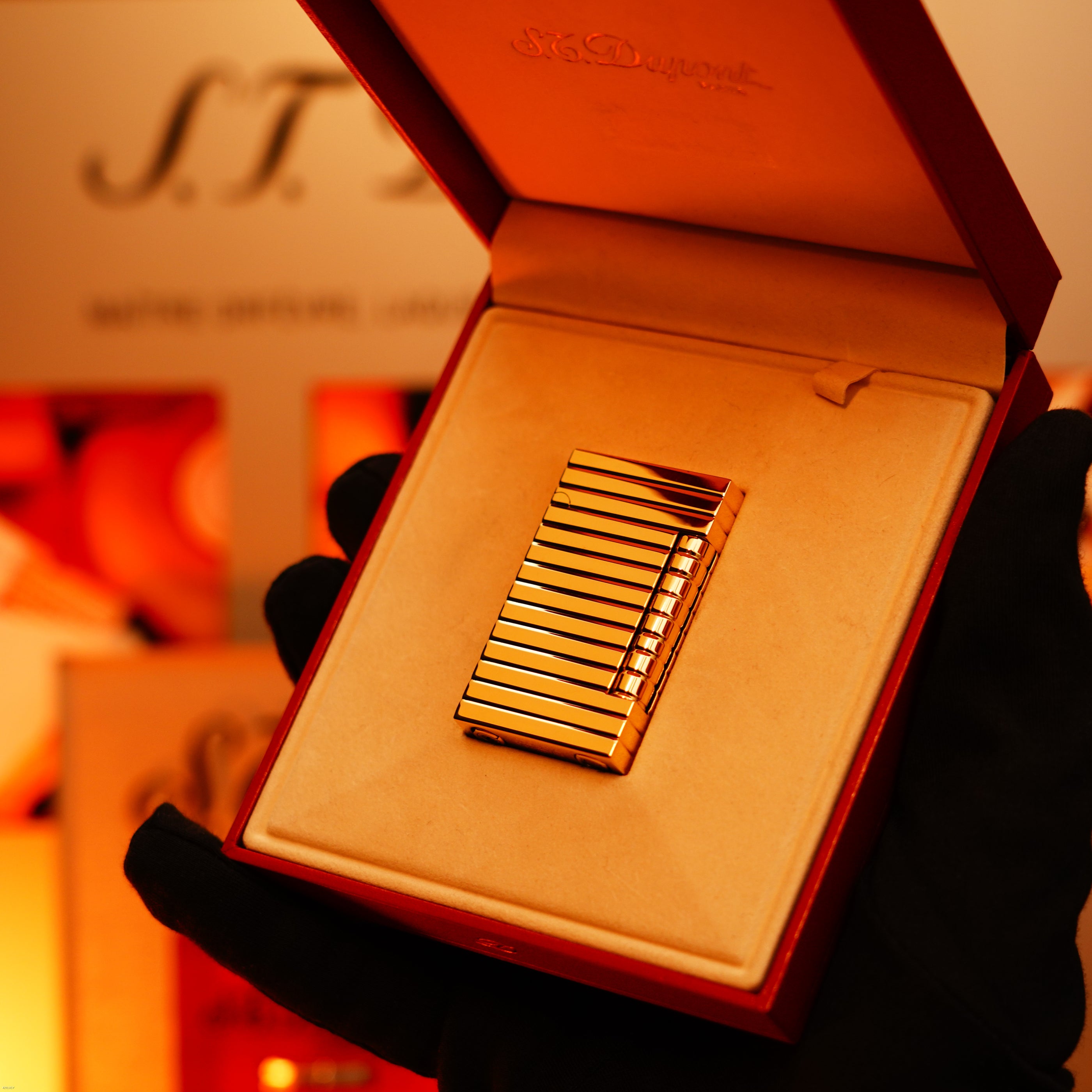 A gloved hand holds an open red box displaying the ultra rare Vintage 1970 ST Dupont Lighter by Lucy Lighter—crafted in solid 18K gold, this 1/1 masterpiece is a true collector's item with a quality guarantee.