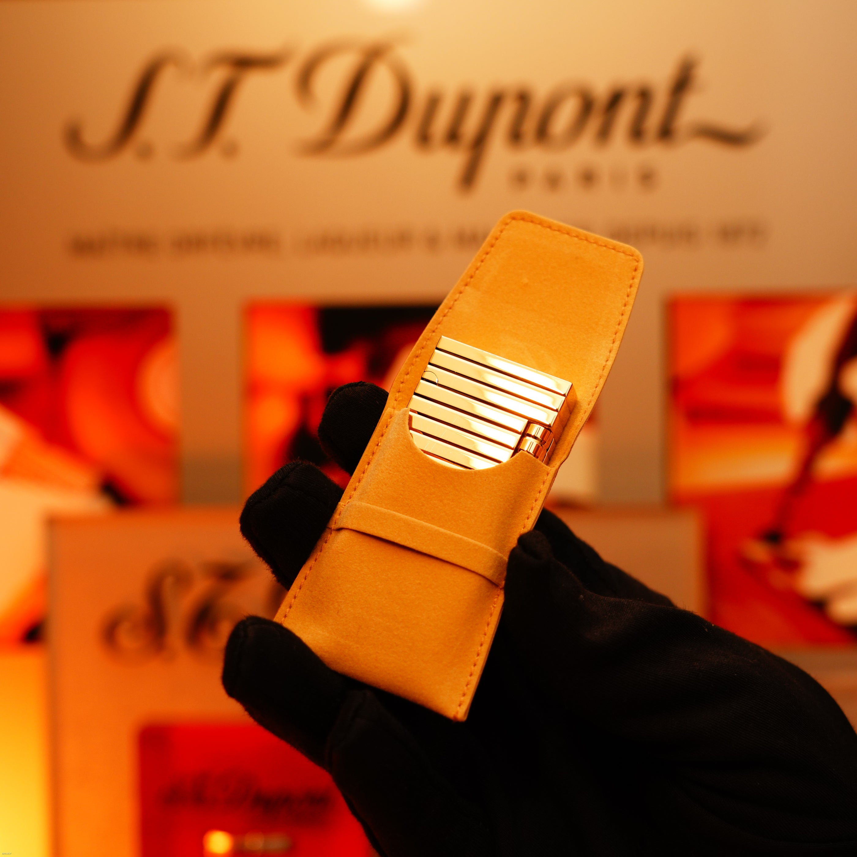 A gloved hand holds the ultra-rare Vintage 1970 ST Dupont Lighter—solid 18K gold by Lucy Lighter—in a tan leather case, with a blurred background display, embodying timeless luxury and exceptional craftsmanship.