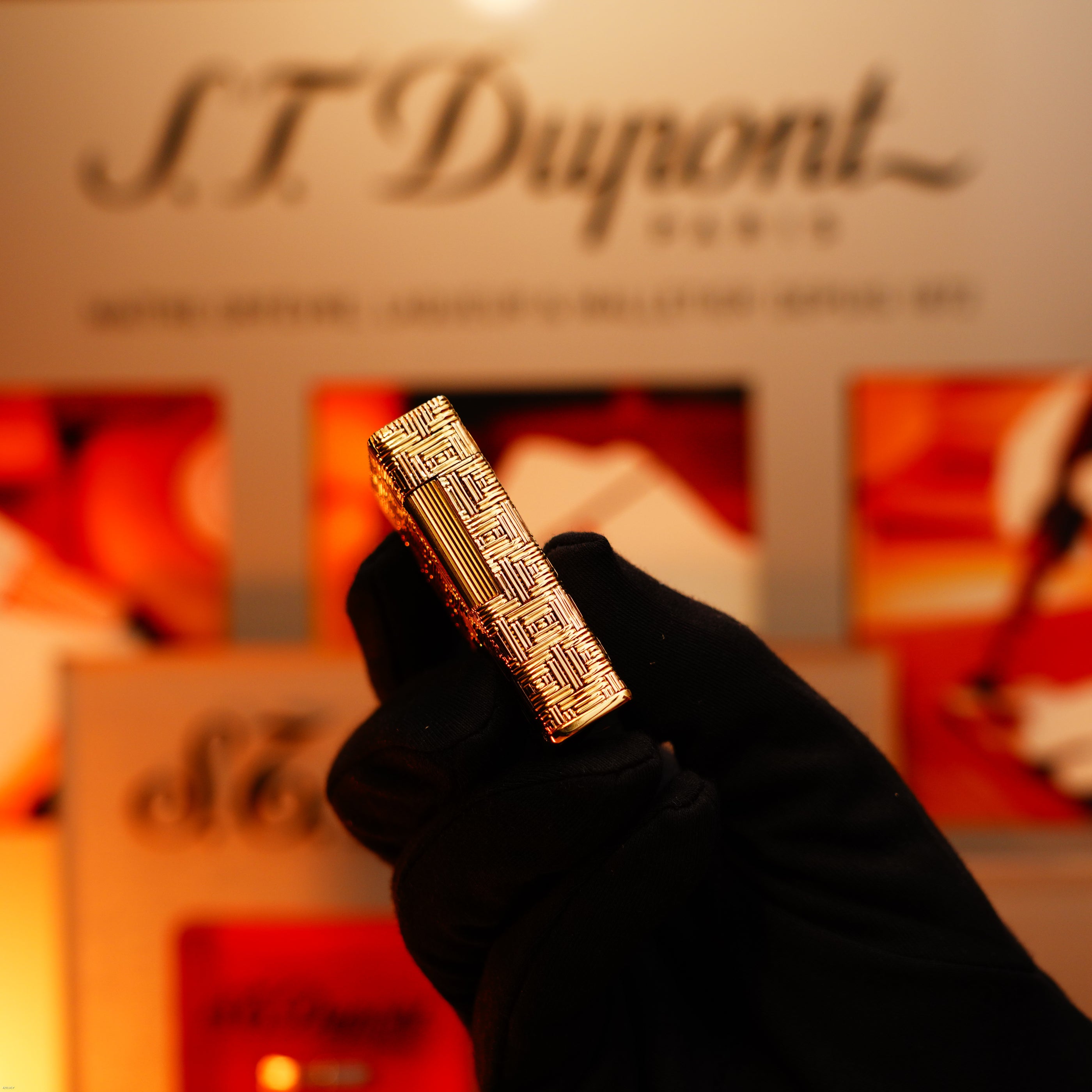 A gloved hand holds a Vintage 1960 Extremely Rare 1/1 Lucy Lighter—Solid 18K Gold, Heavy Early Edition, 750 Hallmarked—with a blurred Lucy Lighter sign and packaging in the background.