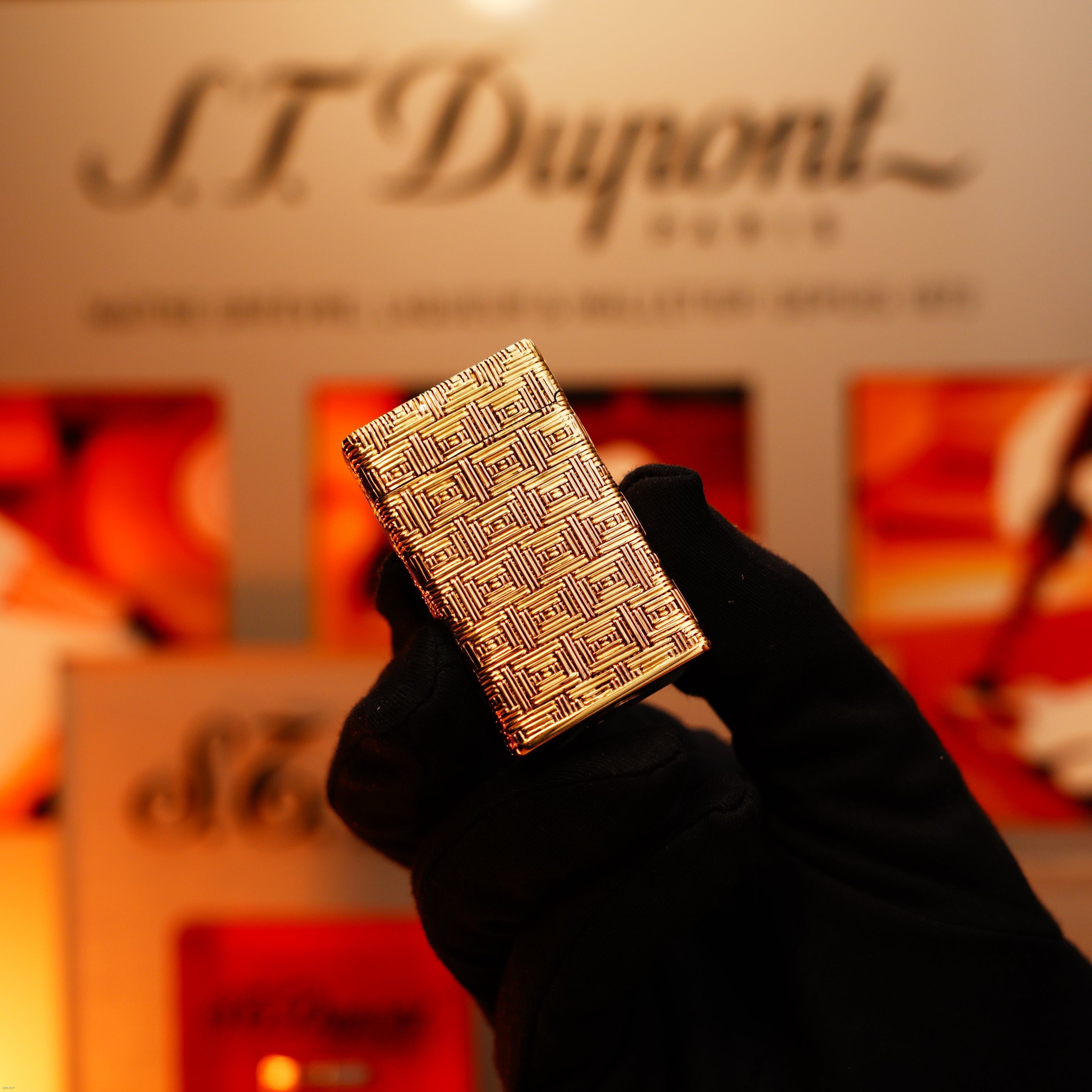 A gloved hand holds the Vintage 1960 Extremely Rare 1/1 St Dupont Lighter in solid 18K gold, heavy early edition (750 hallmarked) by Lucy Lighter, with a working warranty and the S.T. Dupont logo blurred in the background.