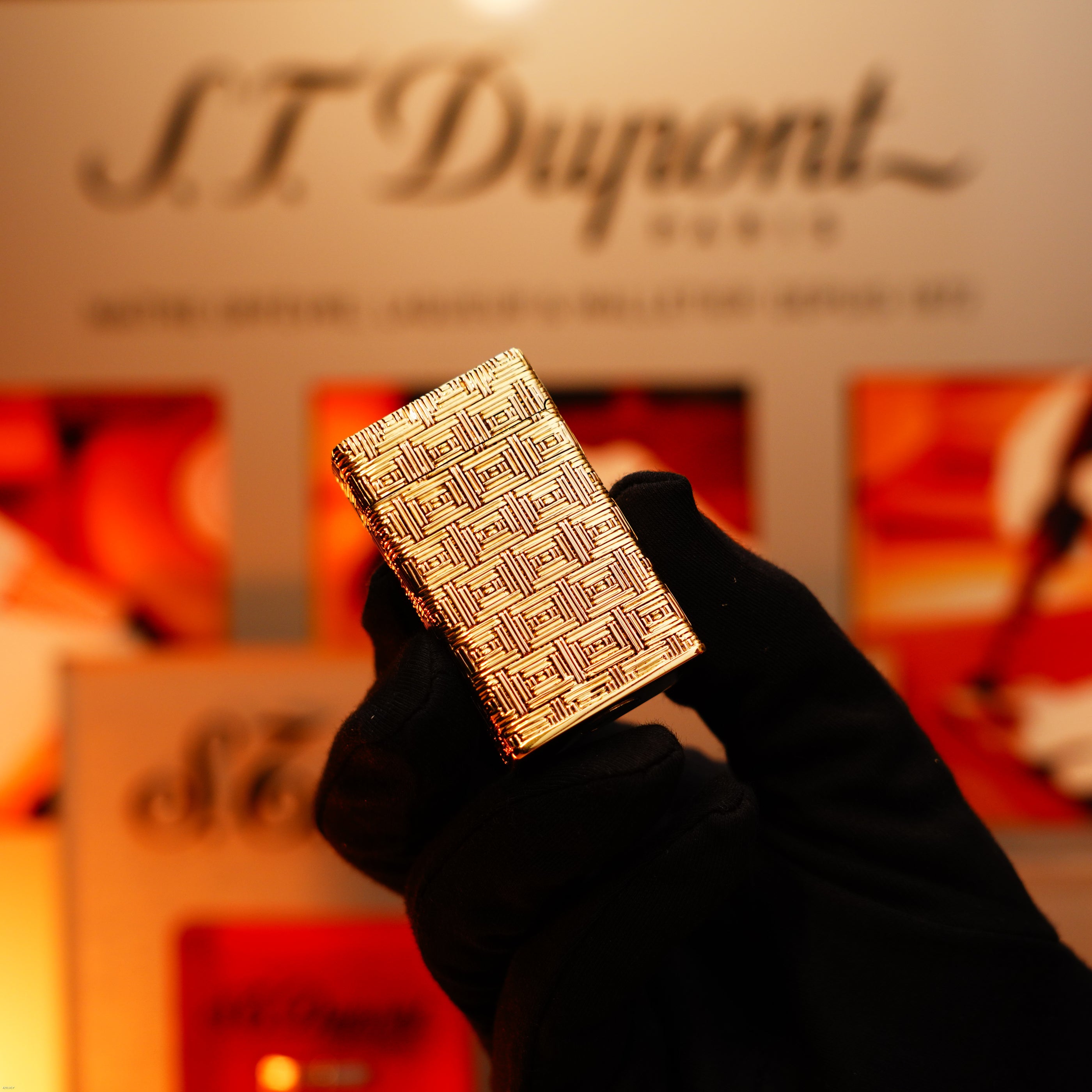 A gloved hand holds the Lucy Lighter Vintage 1960 Extremely Rare 1/1 St Dupont Lighter—solid 18K gold, heavy early edition, 750 hallmarked—with a blurred ST Dupont display behind. Includes working warranty and defect repair for peace of mind.