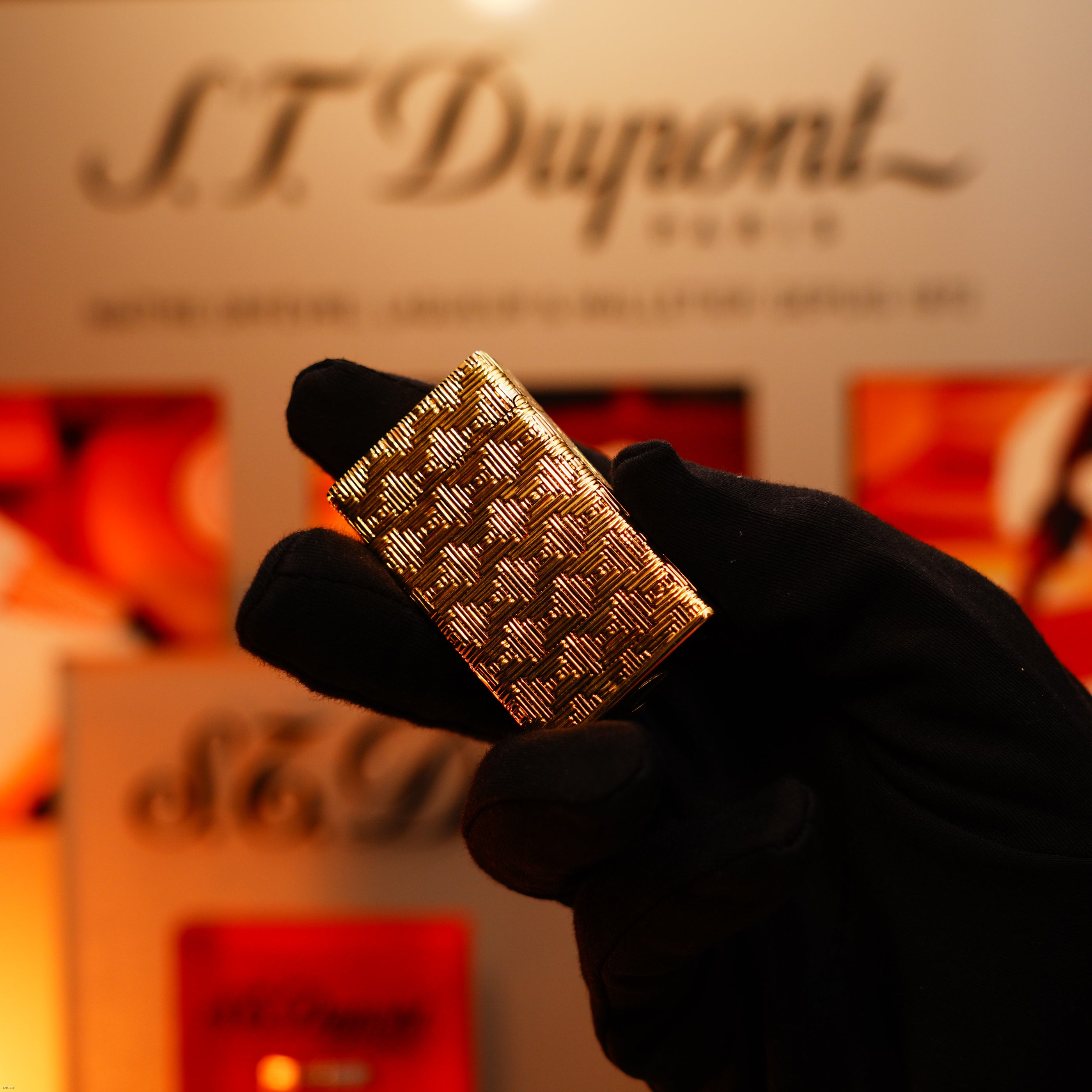 A gloved hand holds a Vintage 1960 Extremely Rare 1/1 Lucy Lighter—Solid 18K Gold, Heavy Early Edition, 750 hallmarked—with a blurred Lucy Lighter branded display in the background.