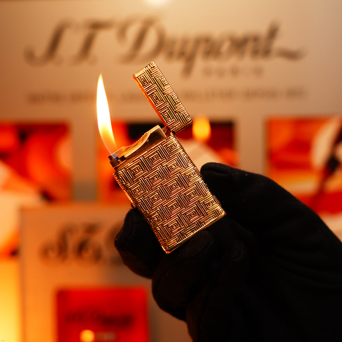 A gloved hand holds open a burning Vintage 1960 Extremely Rare 1/1 St Dupont Lighter—solid 18K gold, heavy early edition, 750 hallmarked—from Lucy Lighter; its branding appears in the softly blurred background.