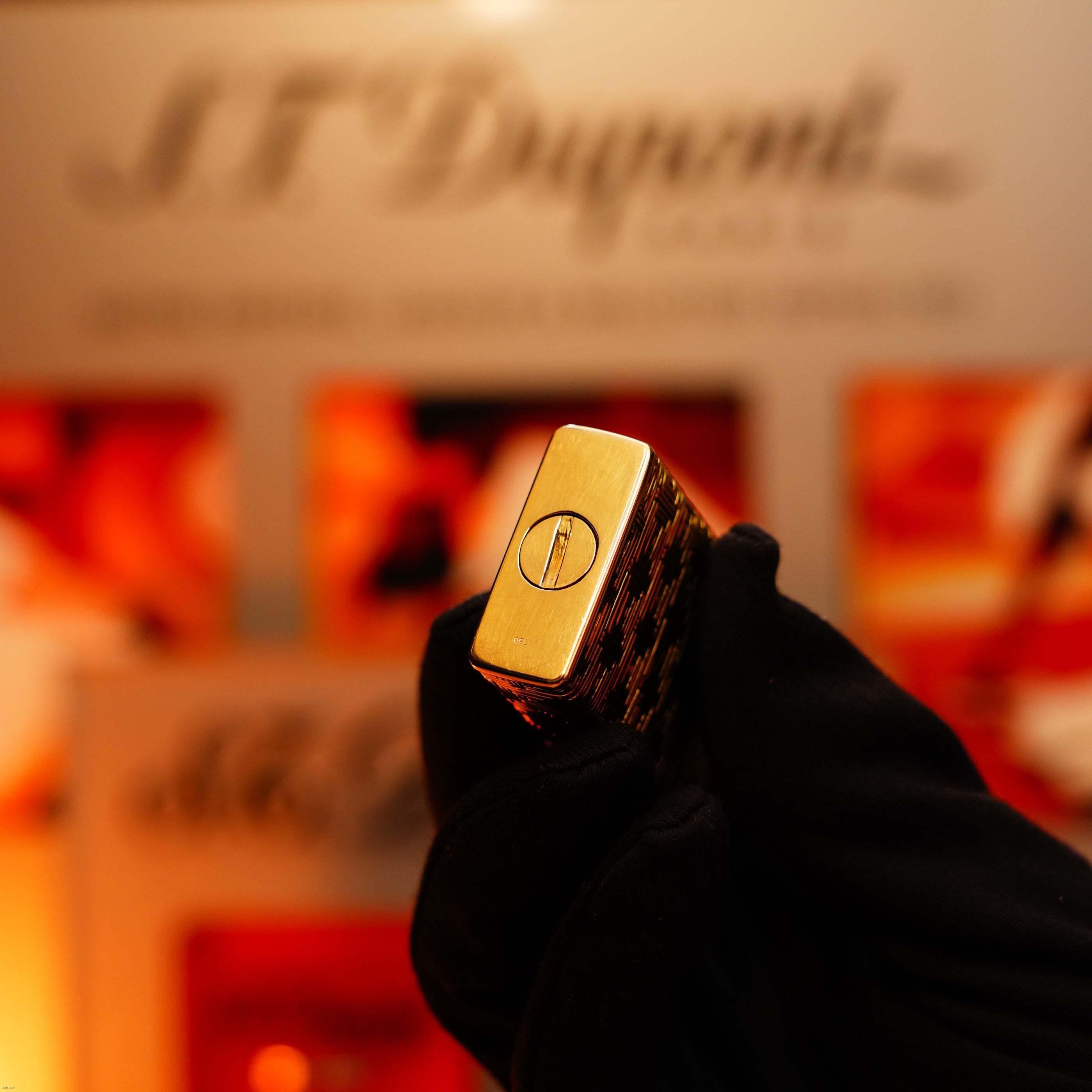 A gloved hand holds the Vintage 1960 Extremely Rare 1/1 Solid 18K Gold Lucy Lighter, Heavy Early Edition, with a blurred Lucy Lighter logo in the background.