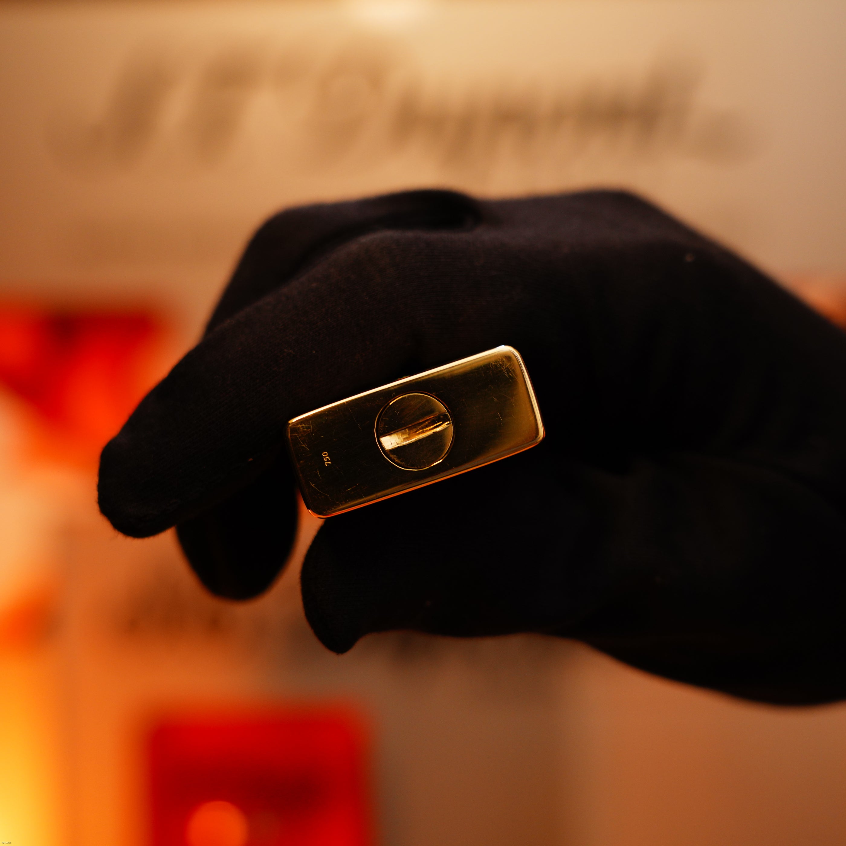 A gloved hand holds the extremely rare Vintage 1960 Lucy Lighter—an early edition St Dupont solid 18K gold lighter, hallmarked 750—against a blurred background.
