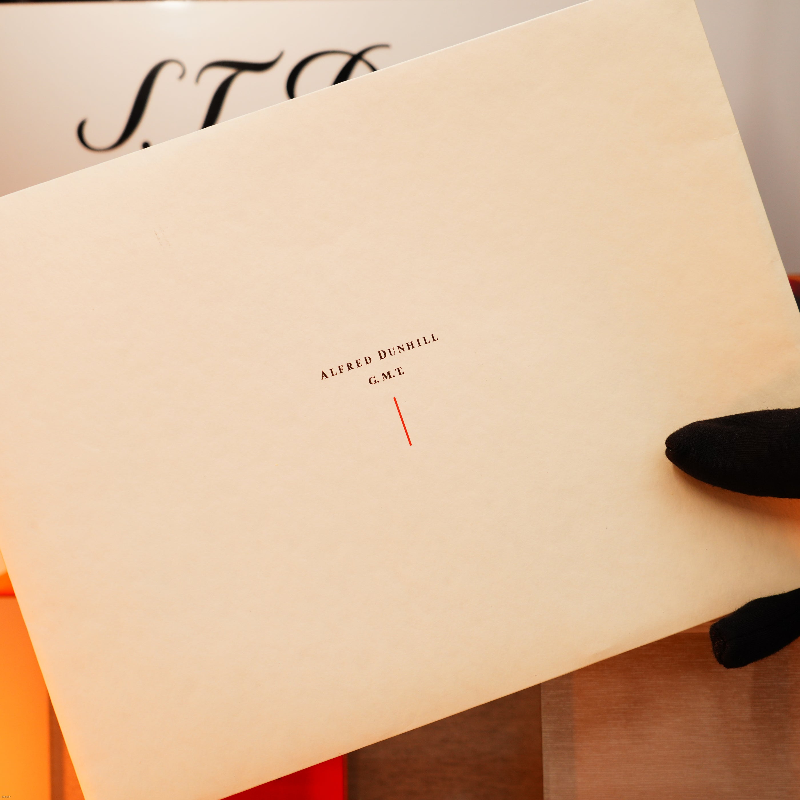 A gloved hand holds an off-white envelope labeled "ALFRED DUNHILL G.M.T."—a quality mark of the Vintage Extremely Rare Alfred Dunhill Full Set GMT Full Solid Stainless Steel Lucy Lighter, a true collector’s item.