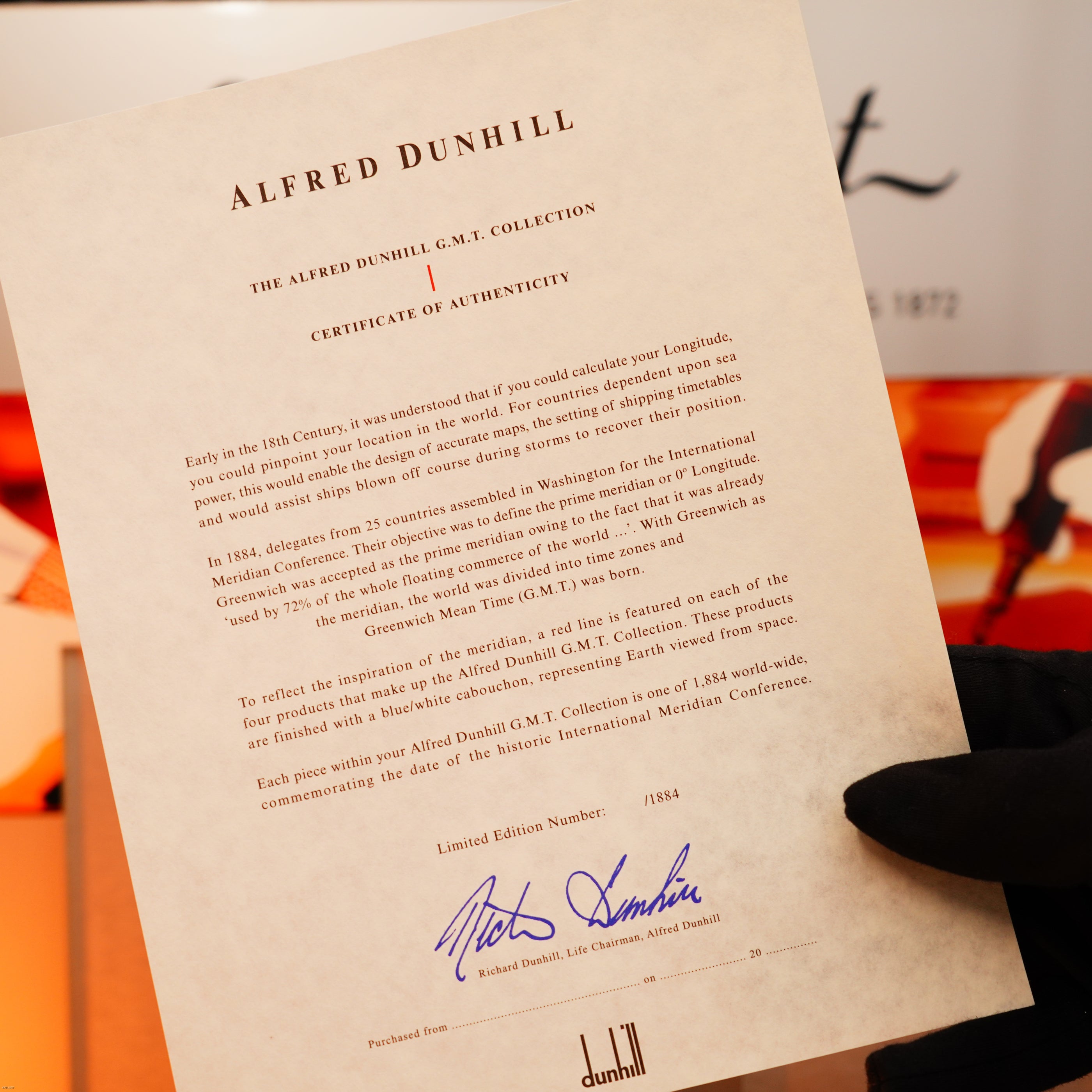 A gloved hand holds a Lucy Lighter certificate of authenticity for the Vintage Extremely Rare Alfred Dunhill Full Set GMT, solid stainless steel with signature, confirming its limited edition and heritage.