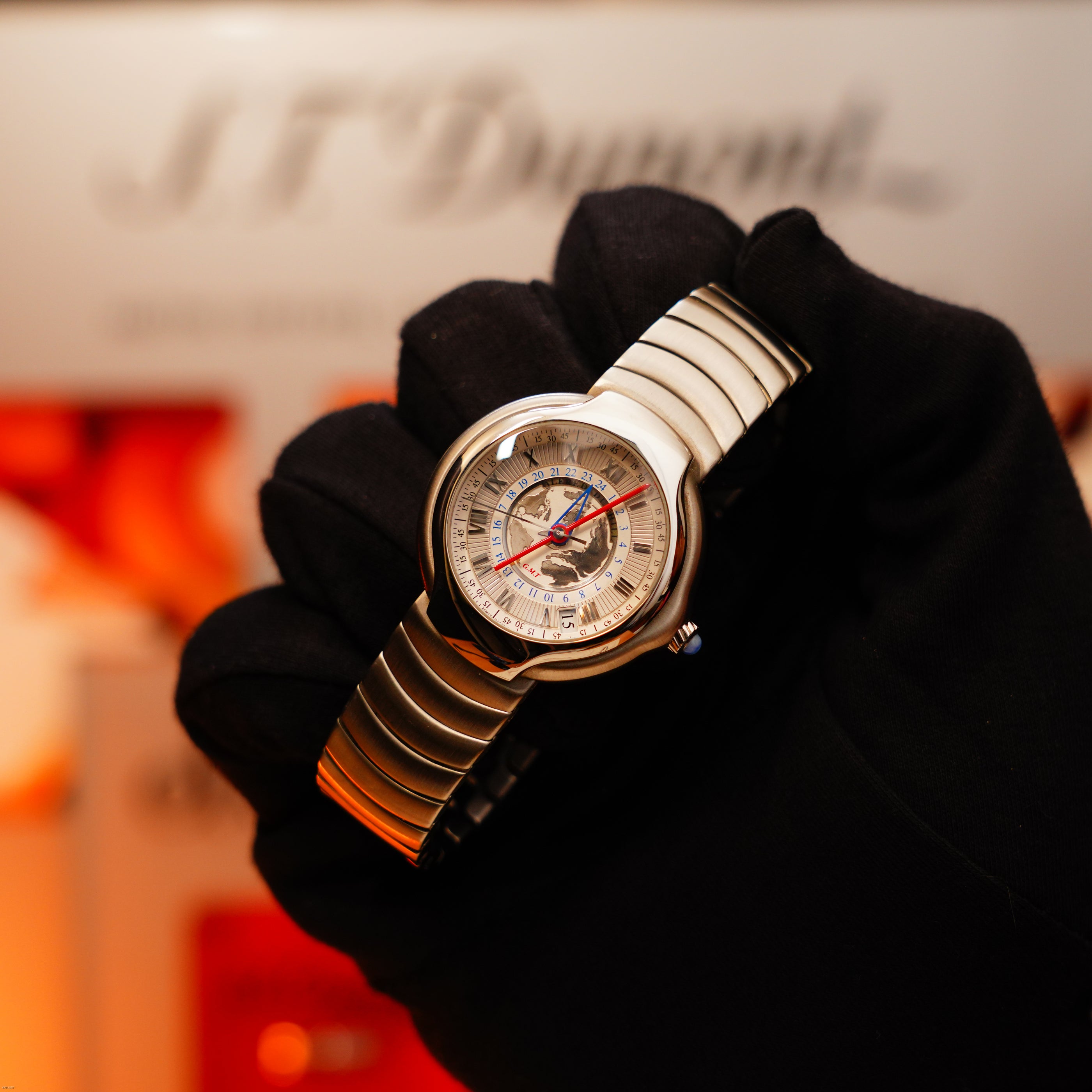 A gloved hand holds the Vintage Extremely Rare Alfred Dunhill Full Set GMT Solid Stainless Steel watch by Lucy Lighter, showcasing signature style and a detailed analog face with multiple dials and red-blue accents.