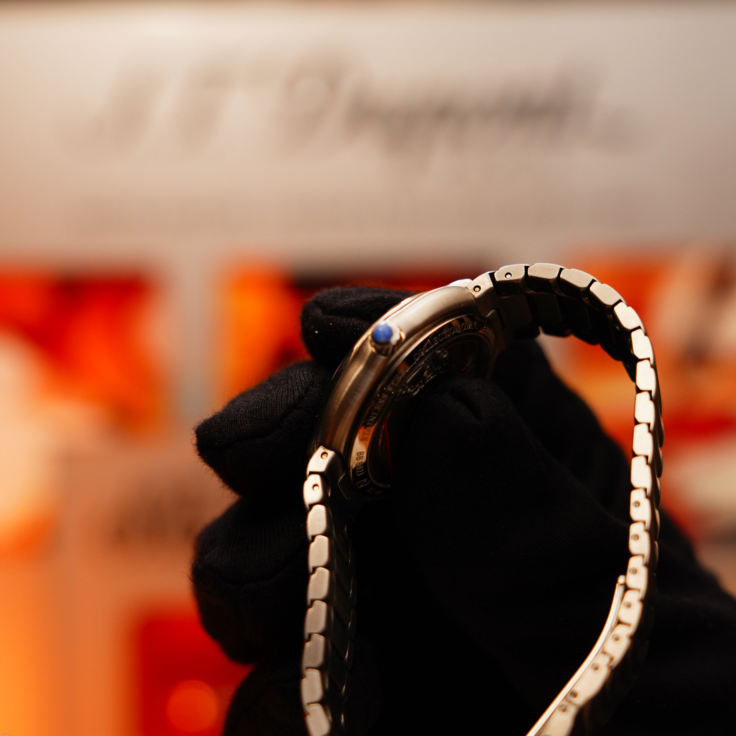 A gloved hand holds the Vintage Extremely Rare Alfred Dunhill GMT Full Solid Stainless Steel watch by Lucy Lighter, with a blue cabochon crown—timeless elegance, complete set, and our 12-month warranty.