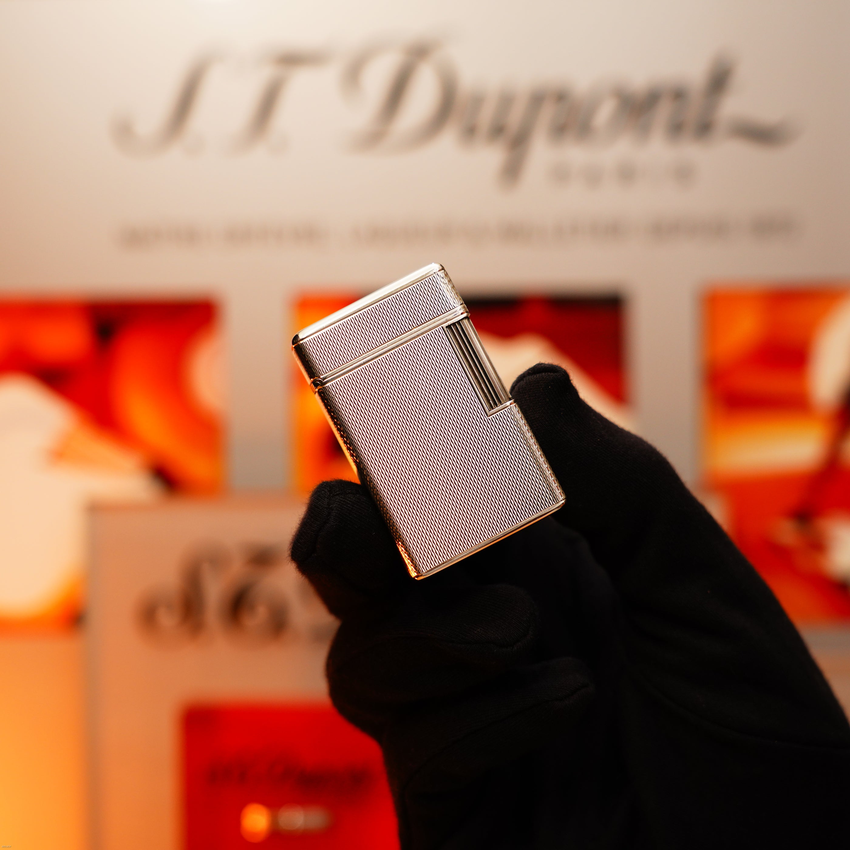 A gloved hand holds the Vintage 1970 Extremely Rare 1/1 De St Dupont Solid 925 Sterling Ligne 1 Heavy Barley Pattern Lighter by Lucy Lighter, with a blurred background highlighting its exclusivity and quality.