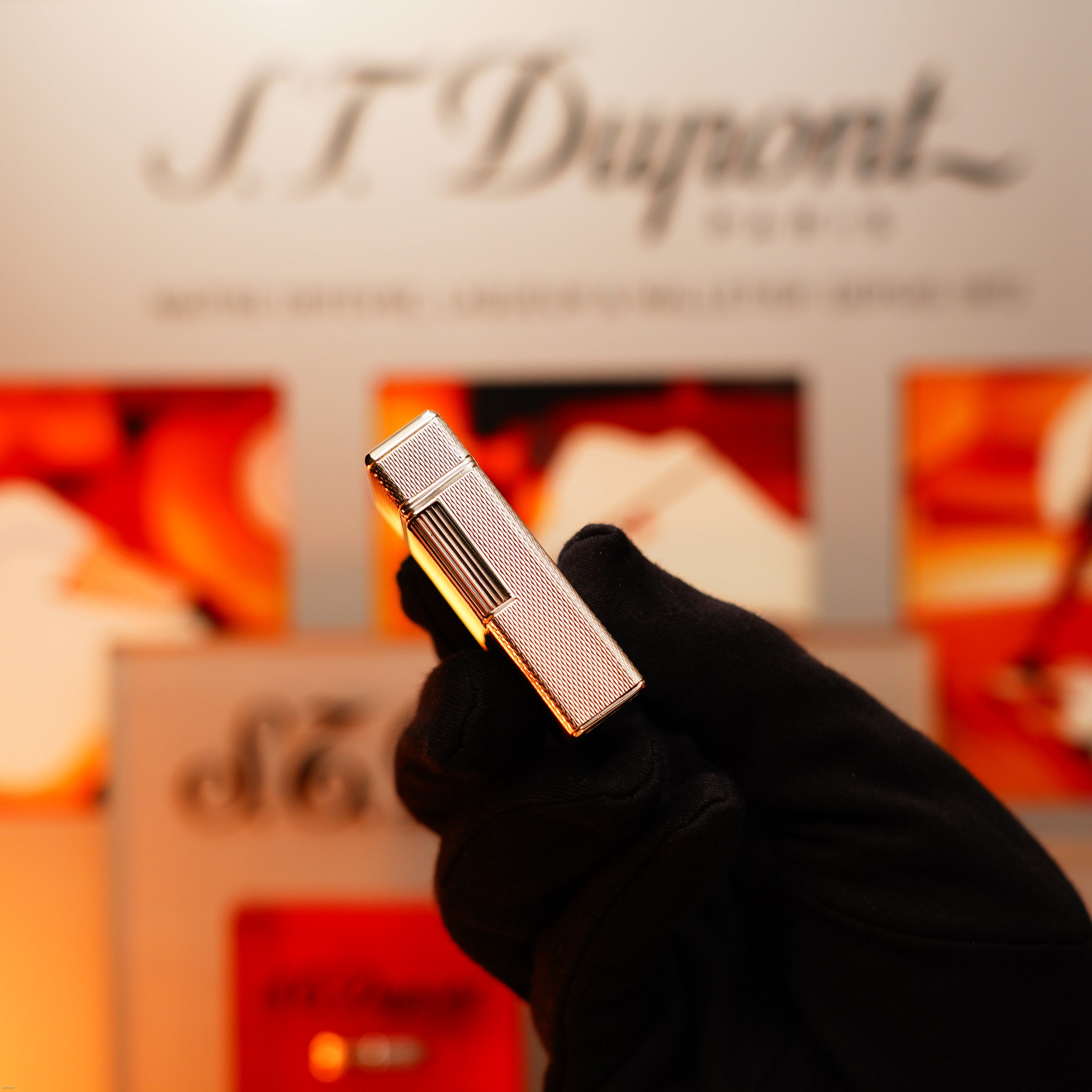 A gloved hand holds the Lucy Lighter Vintage 1970 Extremely Rare 1/1 De St Dupont Solid 925 Sterling Ligne 1 Heavy Barley Pattern Lighter, shown before blurred branding and packaging—includes a 12-month warranty for assurance.