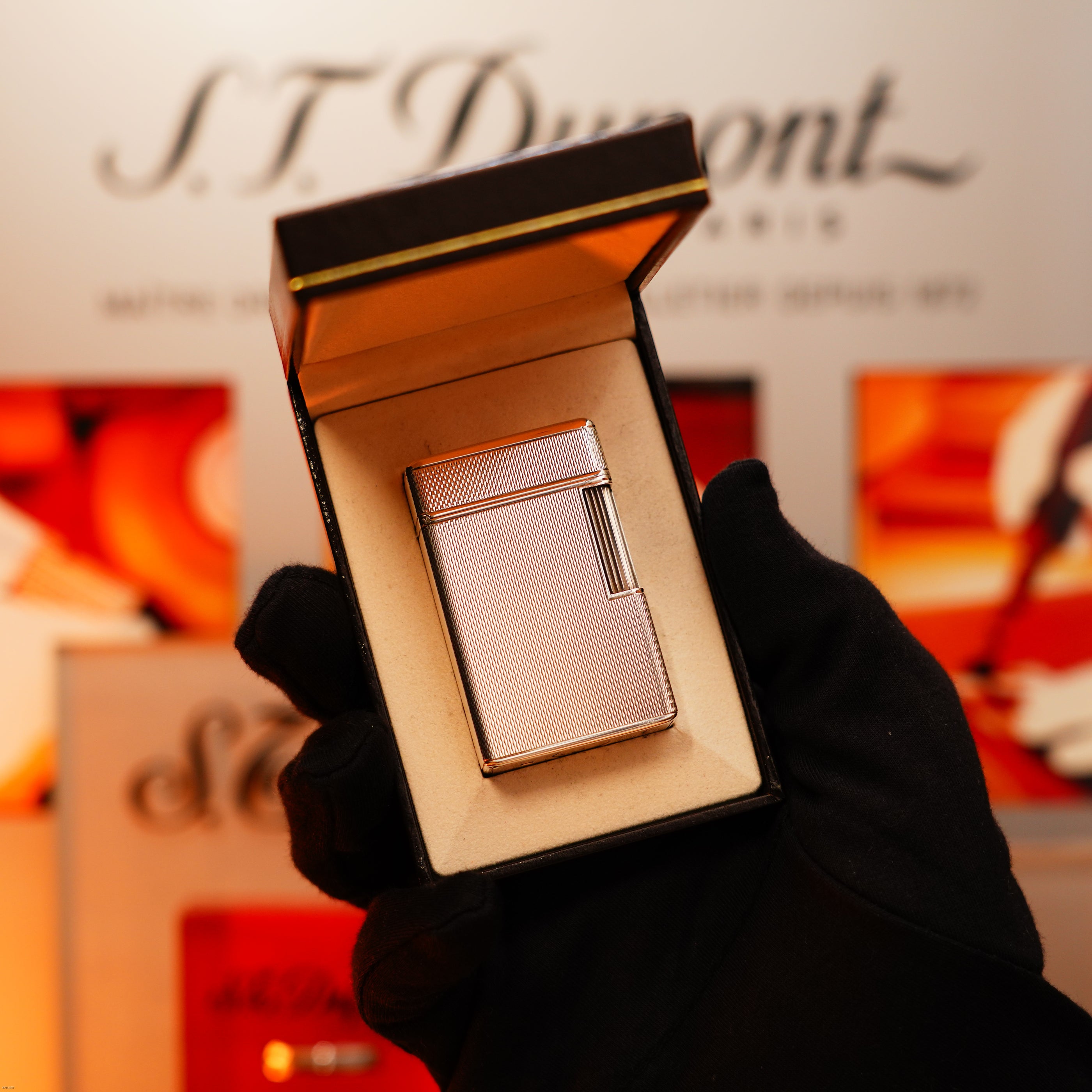 A gloved hand holds an open box showing the Vintage 1970 Extremely Rare 1/1 De St Dupont Solid 925 Sterling Rare Ligne 1 Heavy Barley Pattern Lighter by Lucy Lighter, with luxury and rarity assured in every detail.