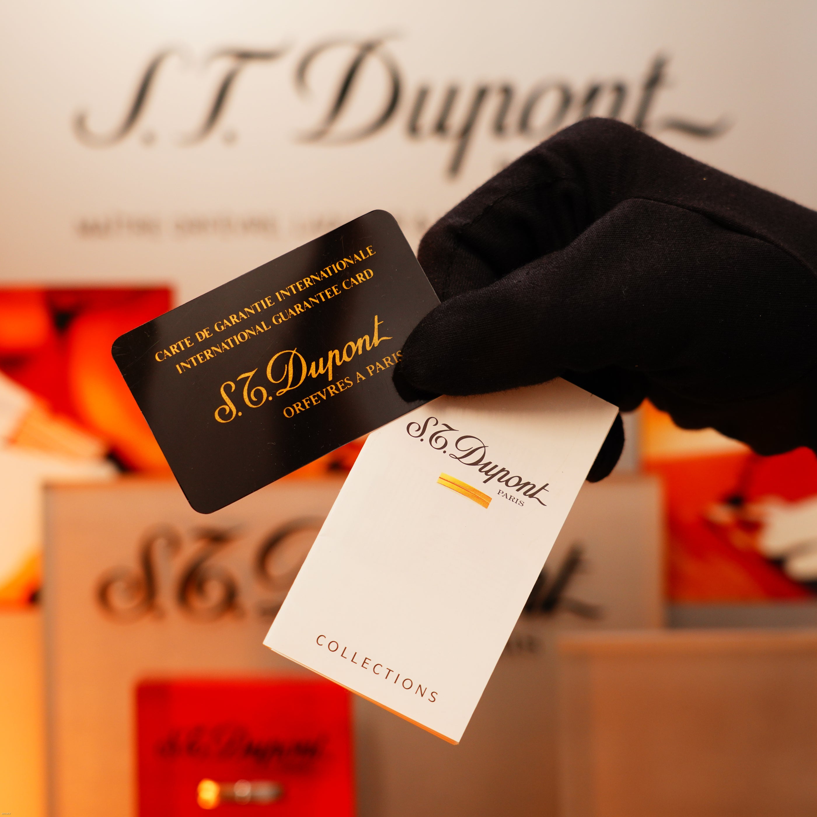 A gloved hand holds an international guarantee card and booklet for the Vintage 1970 Extremely Rare 1/1 De St Dupont Solid 925 Sterling Rare Ligne 1 Heavy Barley Pattern Lighter by Lucy Lighter, showcasing its luxury quality and warranty.