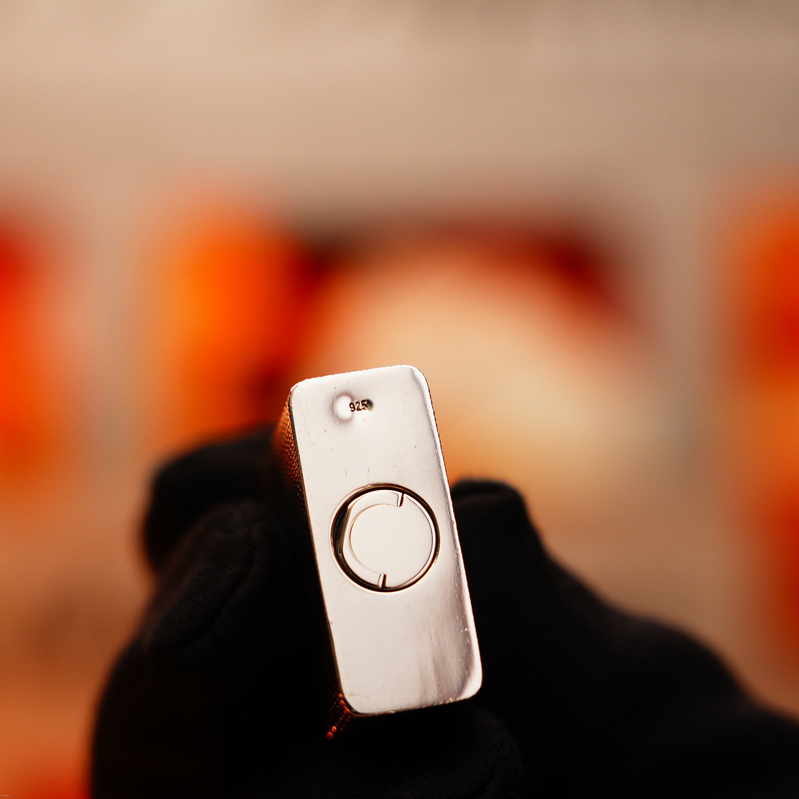 A gloved hand holds the Lucy Lighter Vintage 1970 Extremely Rare 1/1 De St Dupont Solid 925 Sterling Ligne 1 Guilloché Pattern Lighter, a small, elegant device with a circular button and tiny hole, reflecting timeless style and quality.