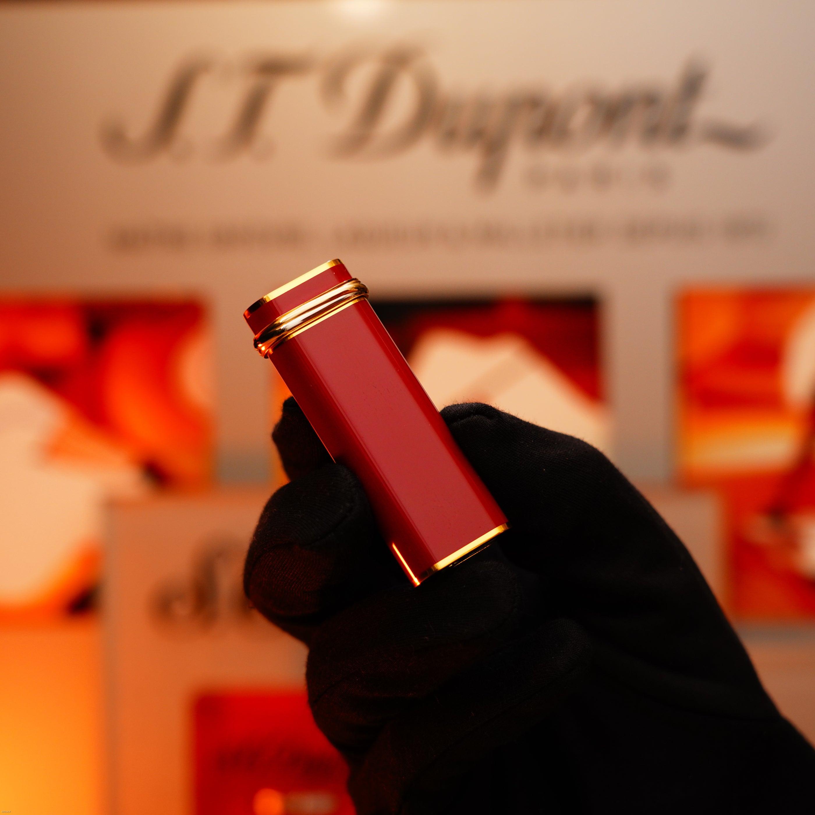 A gloved hand holds a Vintage 1970 Early Cartier Production Heavy Silver Finish Rare Guilloché Pattern Lighter by Lucy Lighter in front of a blurred branded background.