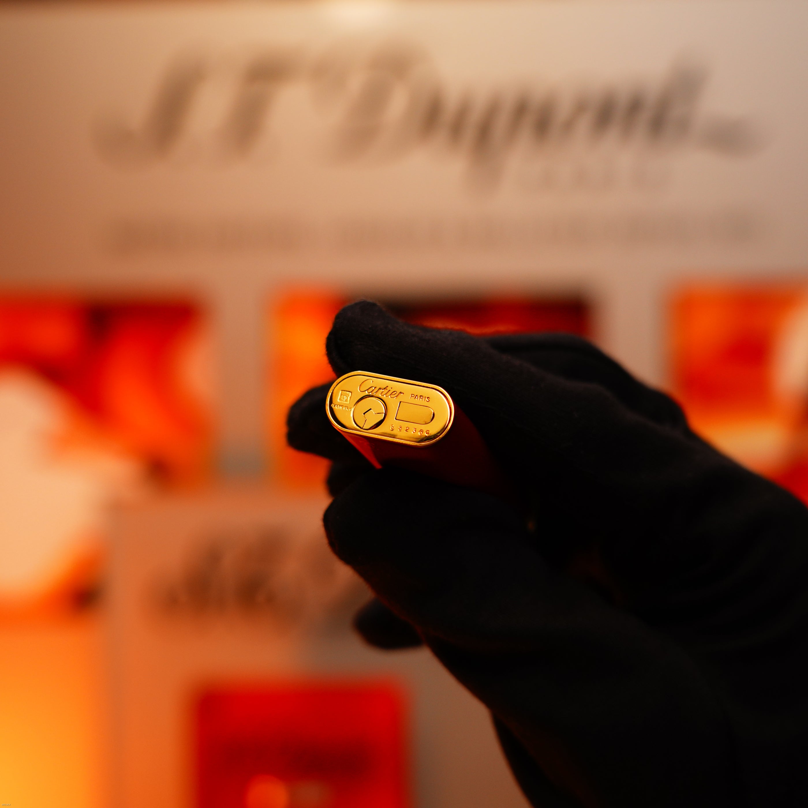 A gloved hand holds a Vintage 1980 Cartier Early Oval 24k Gold Finish Le Must Lighter by Lucy Lighter, with brand detailing visible—reflecting the iconic luxury and quality guarantee that defines Lucy Lighter.