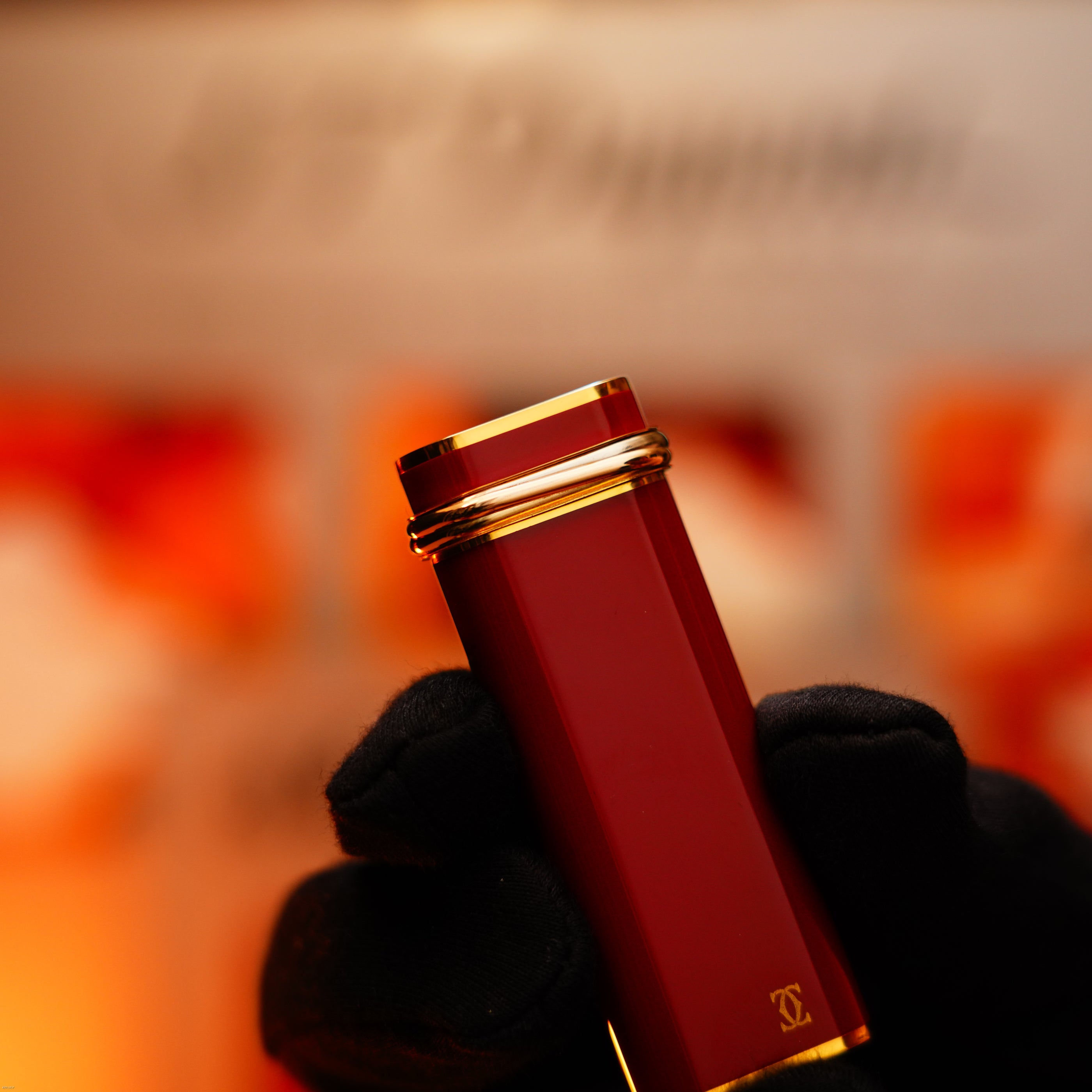 A gloved hand holds a Lucy Lighter Vintage 1970 Early Cartier Production Heavy Silver Finish Rare Guilloché Pattern lighter against a blurred background.