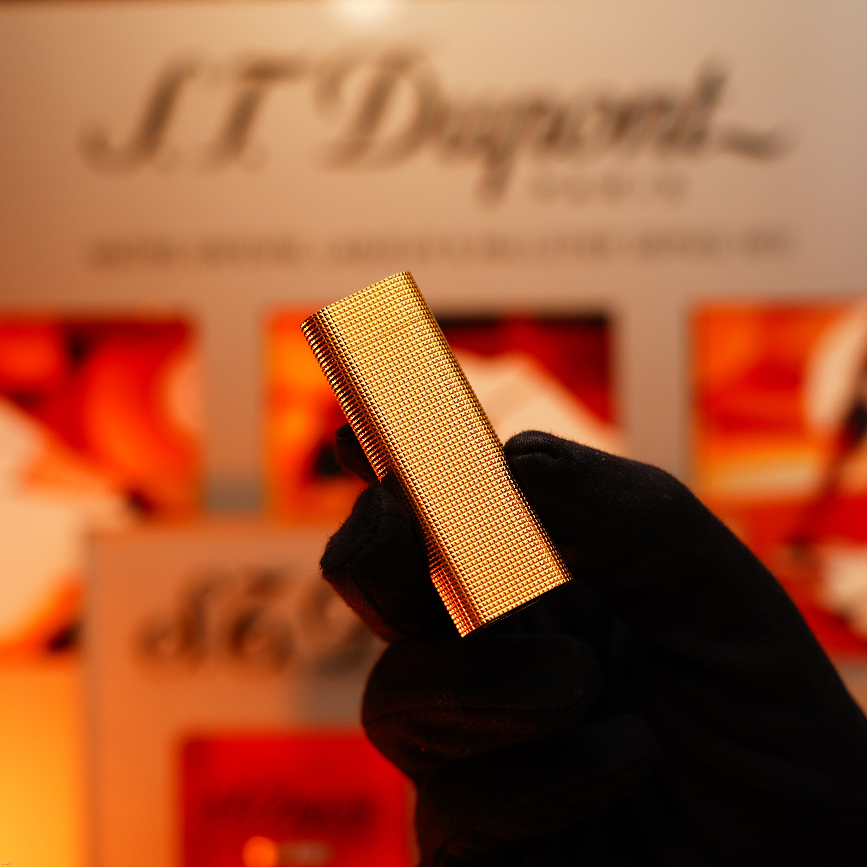 A gloved hand holds a Vintage 1970 Early Cartier Production Heavy Silver Finish Rare Guilloché Pattern Lighter by Lucy Lighter against a blurred background, showcasing refined style and exceptional craftsmanship.