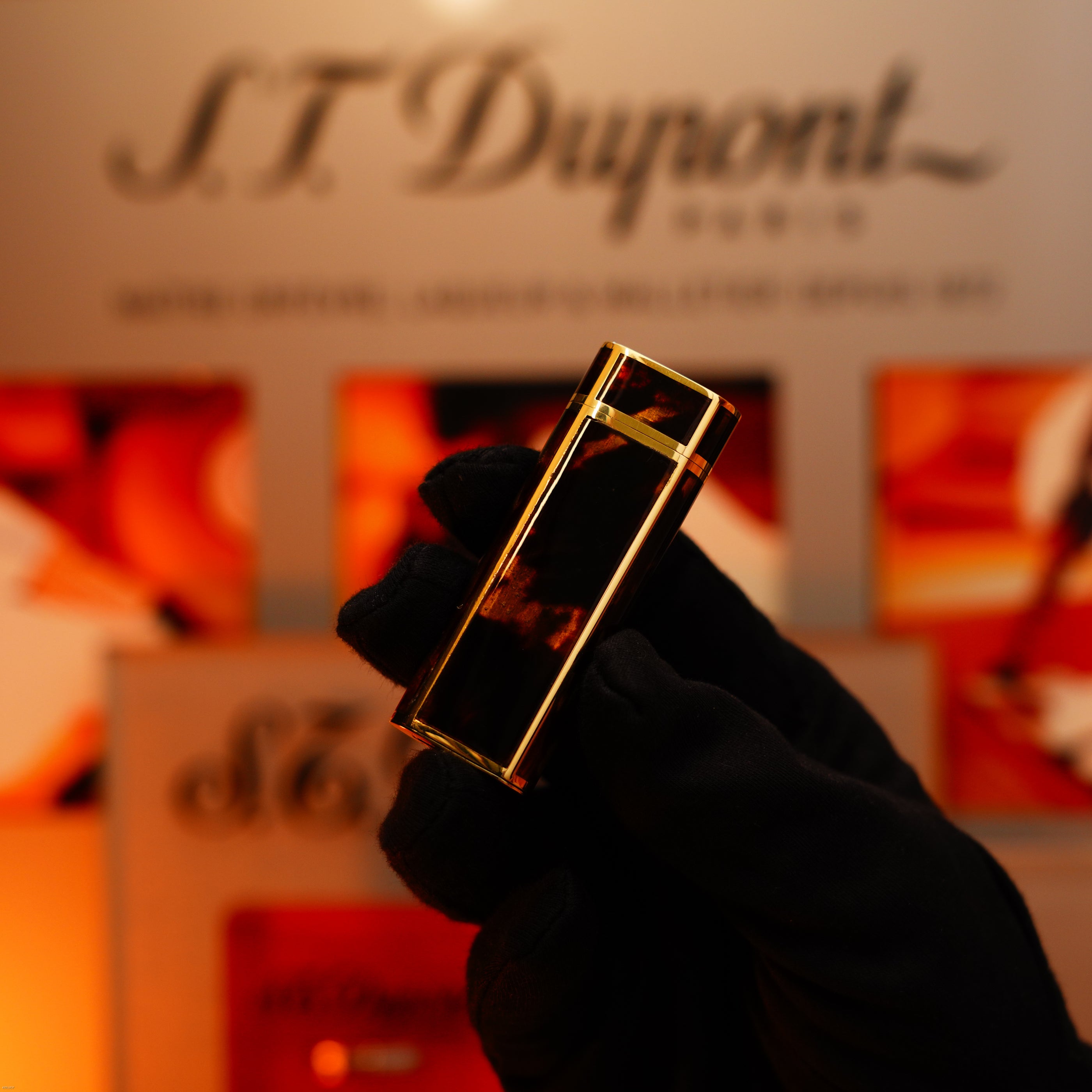 A gloved hand holds a Vintage 1970 Limited Cartier Extremely Rare Solid 18K Gold Tiger’s Eye Resin 750 Hallmarked Lucy Lighter, with the heavyweight rare edition branding visible in the blurred background.