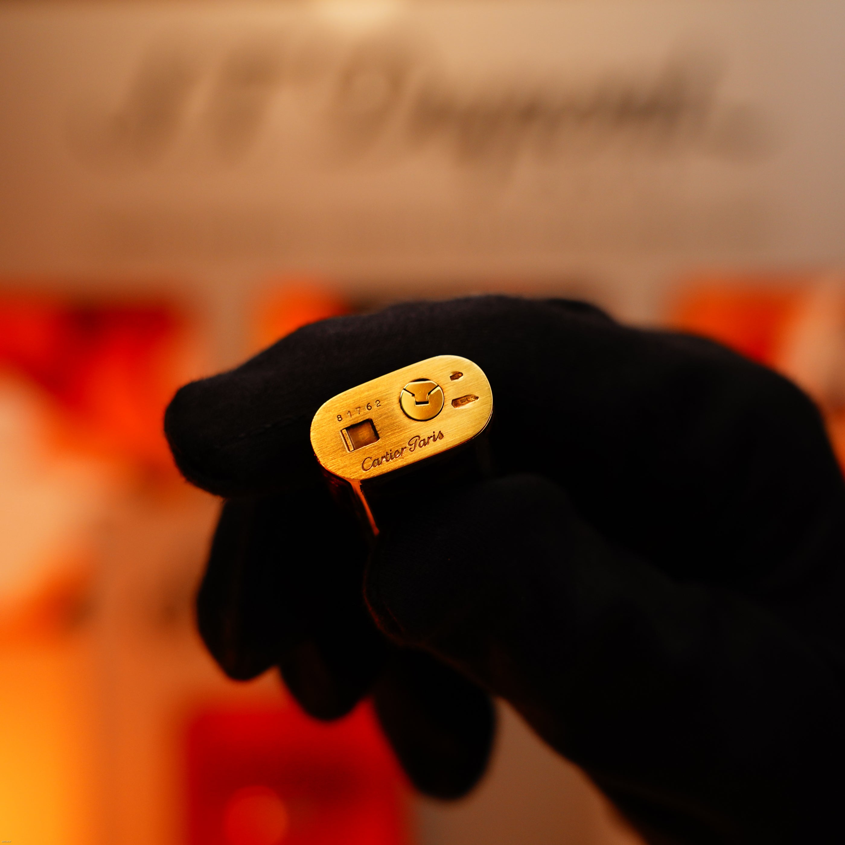 A gloved hand holds a Lucy Lighter Vintage 1970 Limited Extremely Rare Solid 18K Gold Tiger’s Eye Resin 750 Hallmarked 1/1 lighter, with branding engraved on the metal surface.