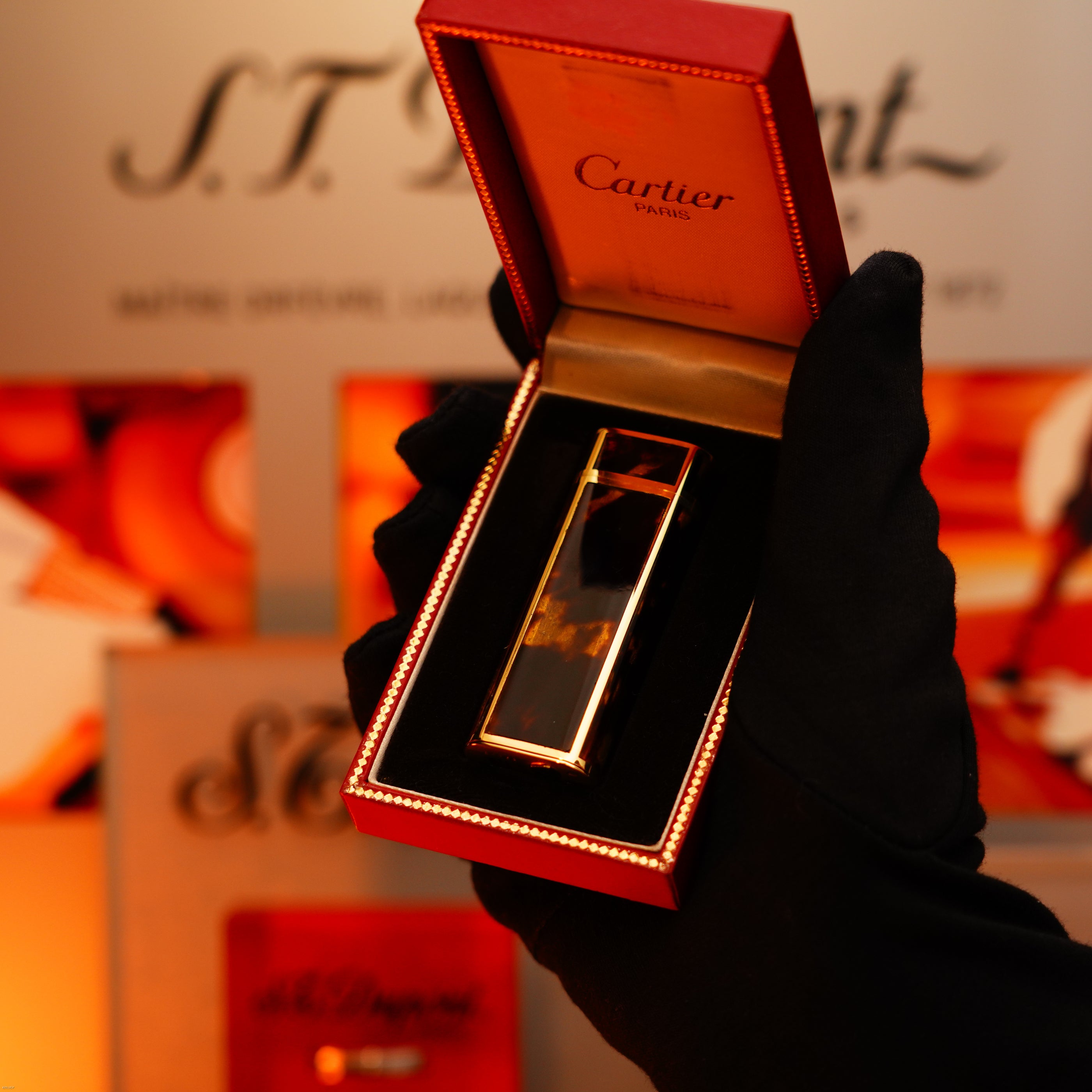 A gloved hand holds an open Cartier Paris box displaying a Vintage 1970 Limited Lucy Lighter, an extremely rare solid 18K gold and Tiger’s Eye resin heavyweight lighter, hallmarked 750 and marked as 1/1.