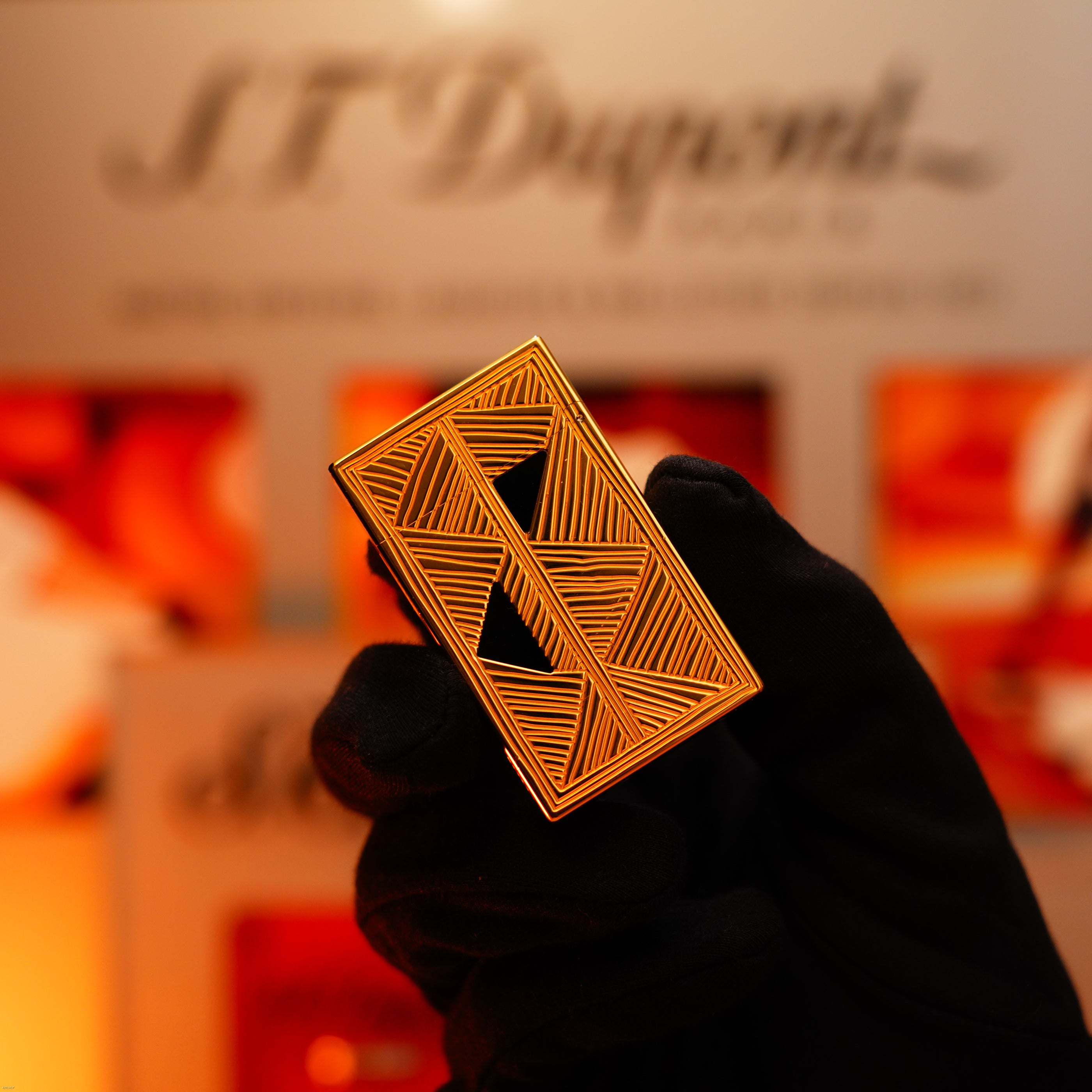 A gloved hand holds the Lucy Lighter Vintage 2000 Limited Edition Heavy 24k Gold Finish Africa Natural Lacquer Large Ligne 2 Lighter, set against a blurred background—an emblem of luxury and quality.