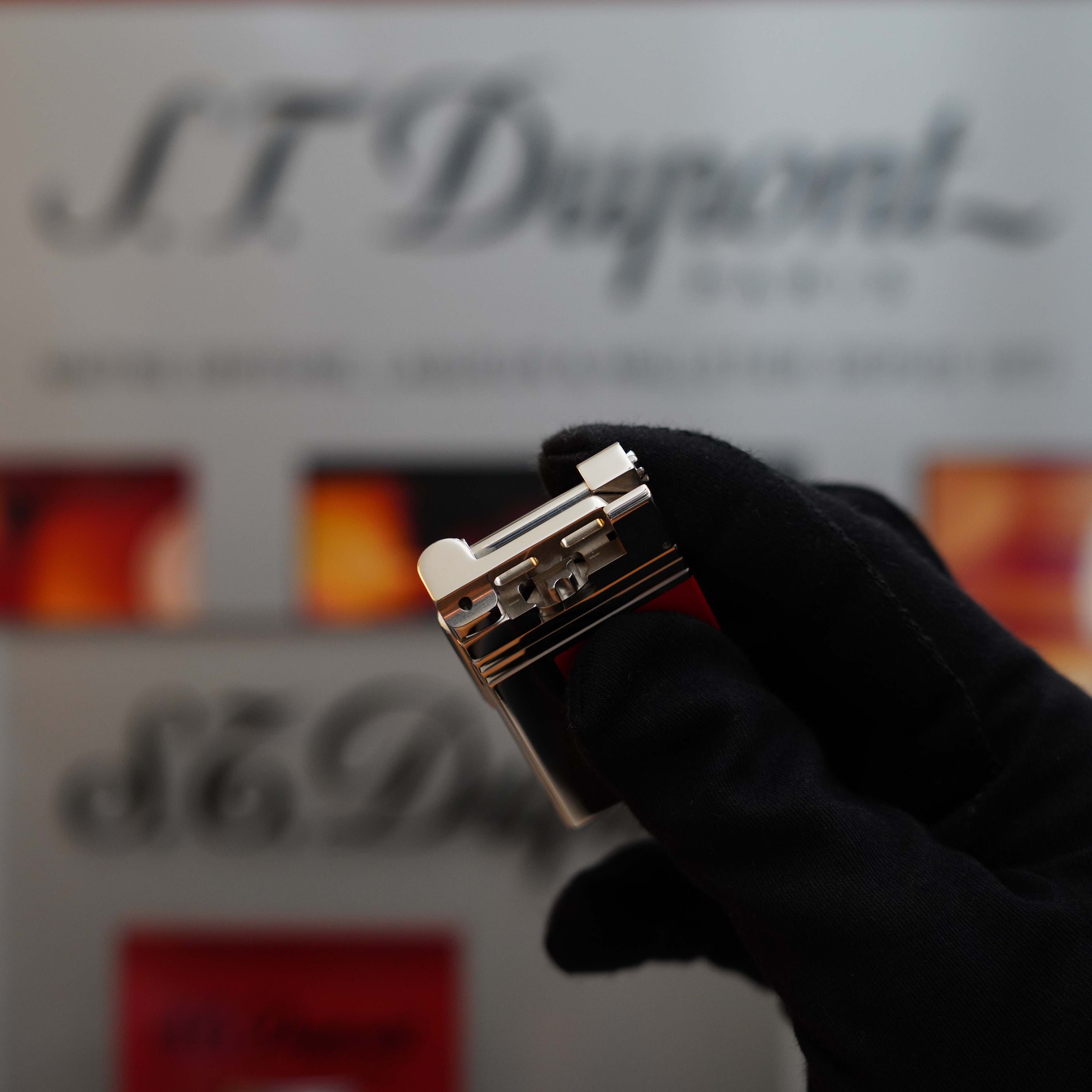 A gloved hand holds a silver Vintage 1999 St Dupont Urban Limited Edition Platinum finish natural Red Lacquer lighter, a true collector's item, in front of a blurred background with the S.T. Dupont logo.