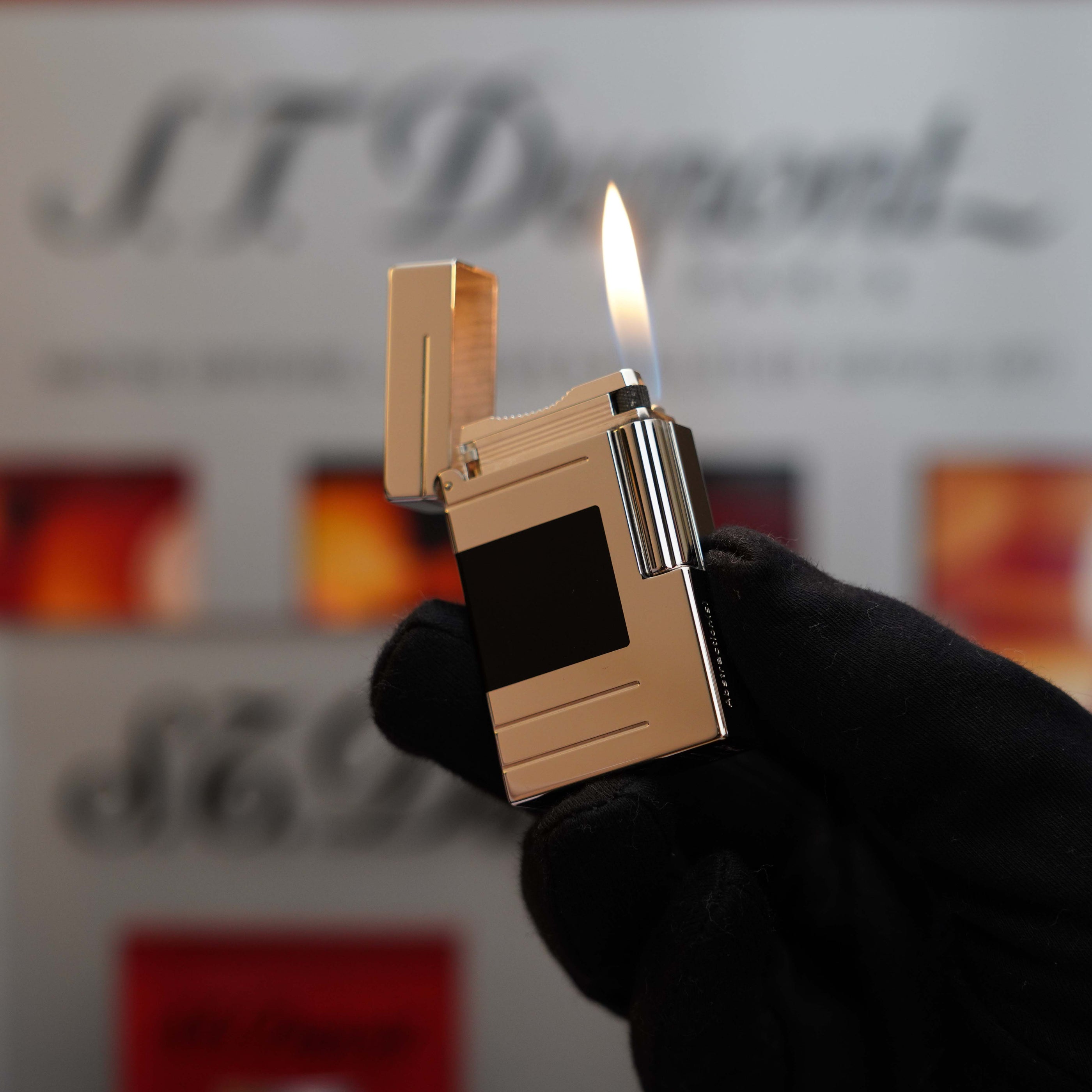 A gloved hand holds a lit, Vintage 1999 S.T. Dupont Ligne 1 Limited Edition Platinum finish natural Black Lacquer lighter against a blurred background.