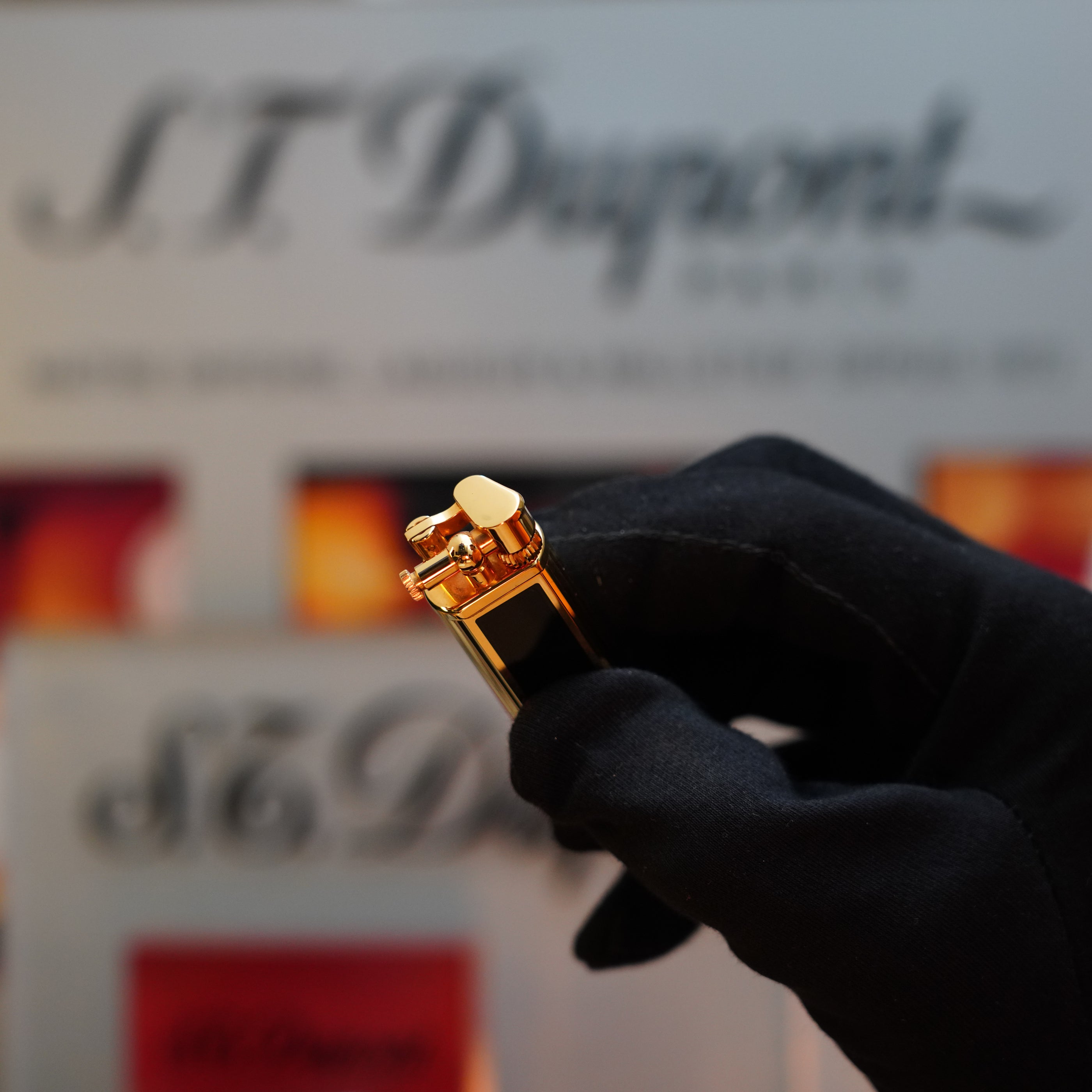 A black-gloved hand holds a vintage 1980 Dunhill Unique Sylfide 24k Heavy Gold Natural Lacquer lighter, with the Dunhill logo visible in the blurred background.