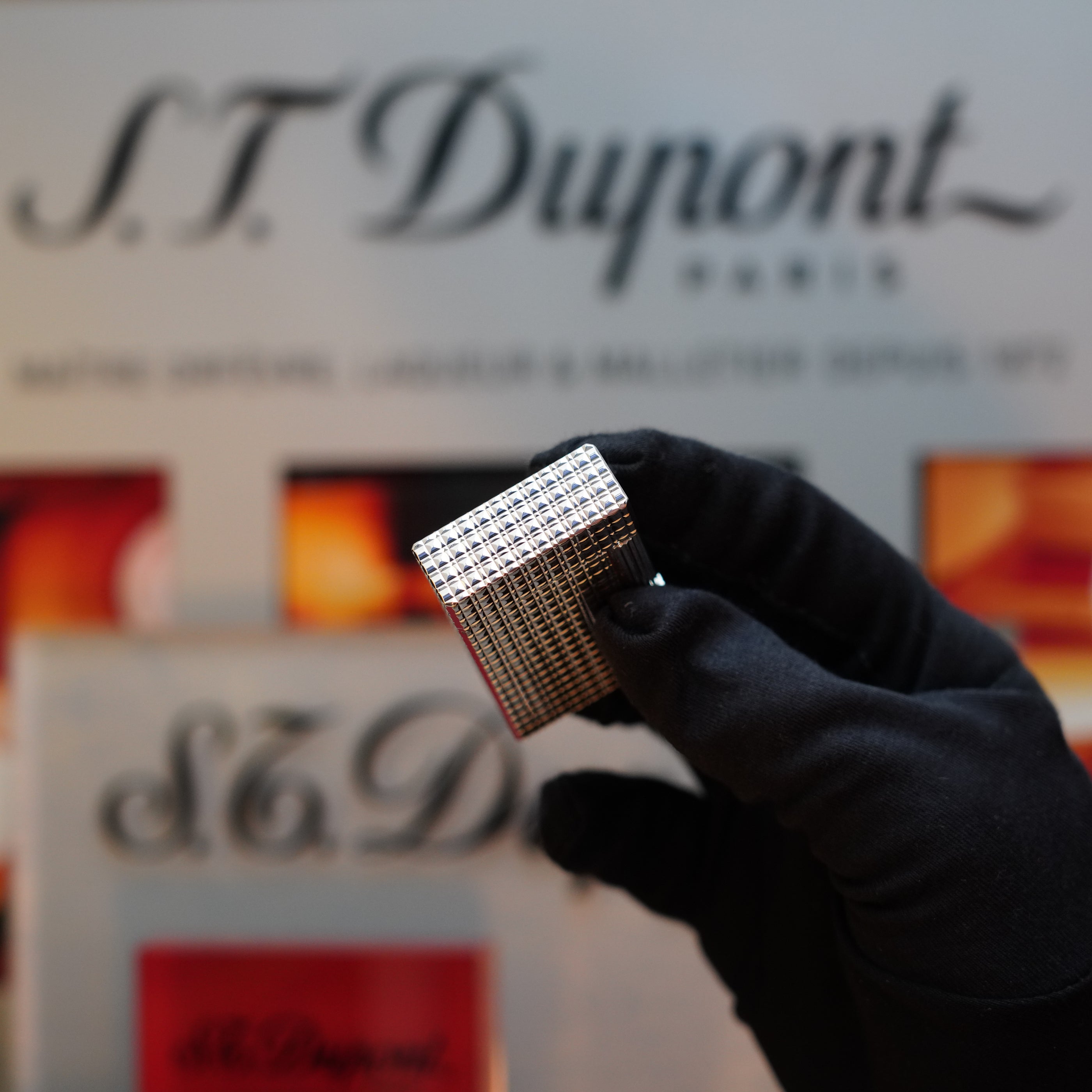 A person wearing a black glove holds a silver 1980 S.T. Dupont Silver Finish Rare Pattern Large Size Ligne 1 lighter, a true collector's item.