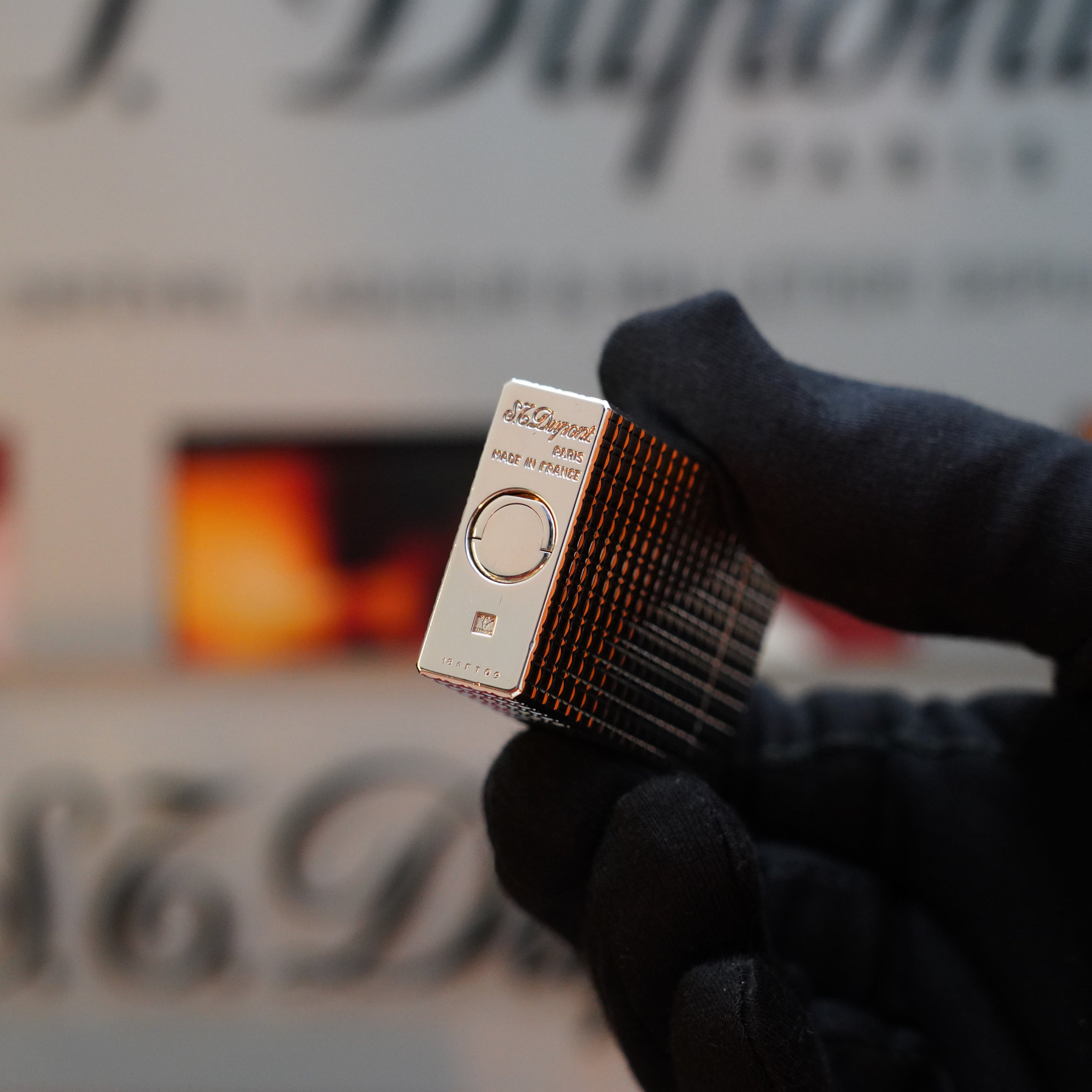 A gloved hand holding a vintage 1980 St Dupont Silver Finish Rare Pattern Large Size Ligne 1 lighter. The engraved text "S.T. Dupont Paris" is visible on the collector's item, highlighting its prestige as part of the esteemed Ligne 1 series.