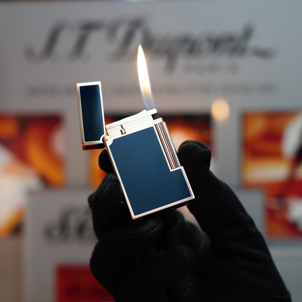 A gloved hand holding a lit S.T. Dupont lighter, designed with a captivating dark blue lacquer and heavy 24k rose gold finish, from the vintage 1970 Ligne 2 collection.
