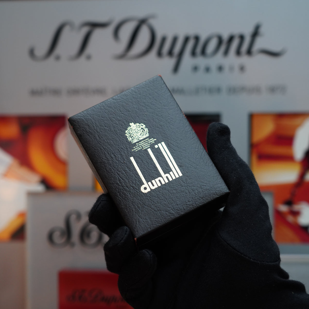 A gloved hand presents a black box from Dunhill against a blurred backdrop, subtly showcasing the "Vintage Dunhill Rollagas Limited Edition Solid Silver 925 Lines with Hallmark" lighter, crafted in Solid Silver 925.