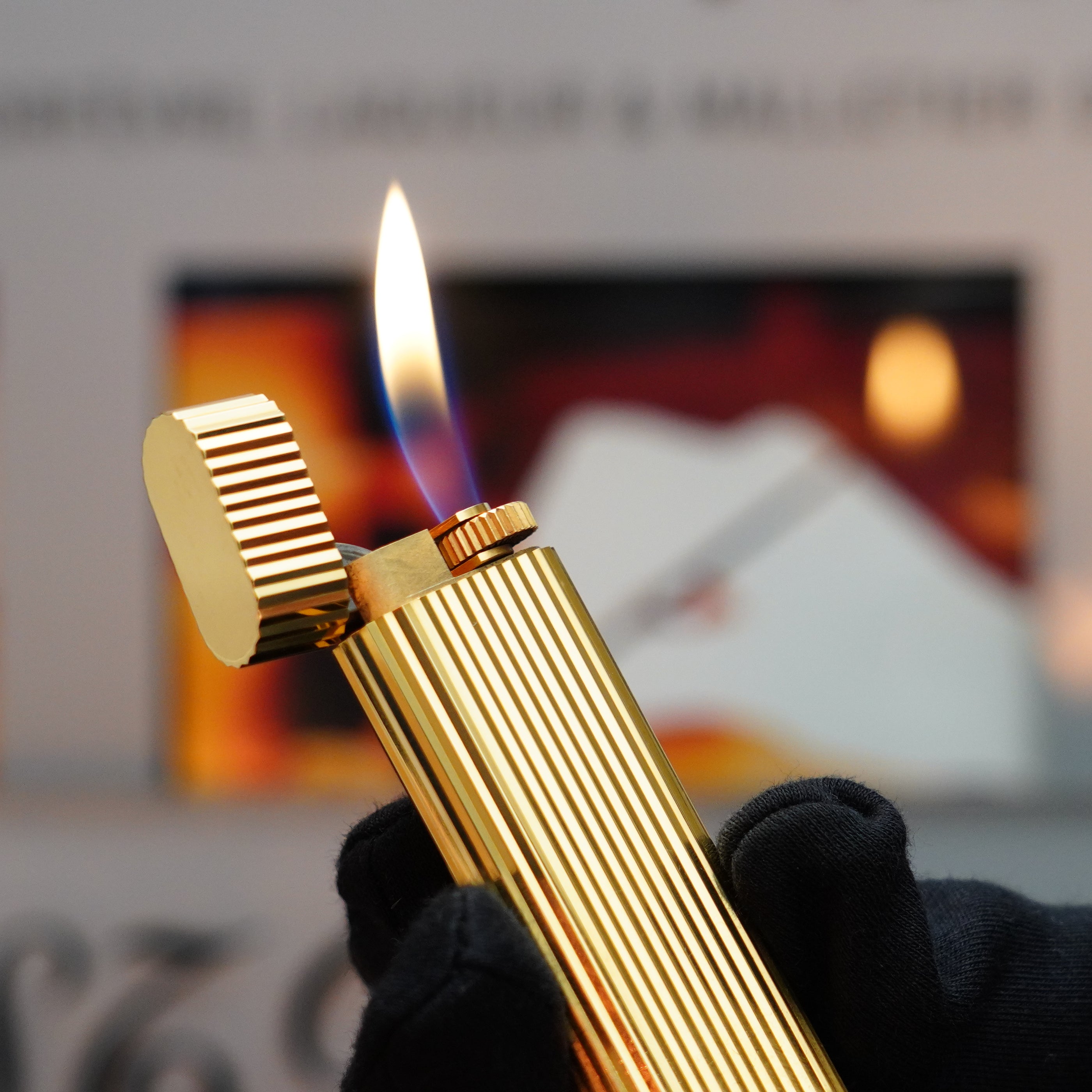 A gloved hand delicately holds a lit lighter with a ribbed design, showcasing the exquisite 24k gold finish of the Vintage 1980 Cartier Vertical Line Le Must Lighter.