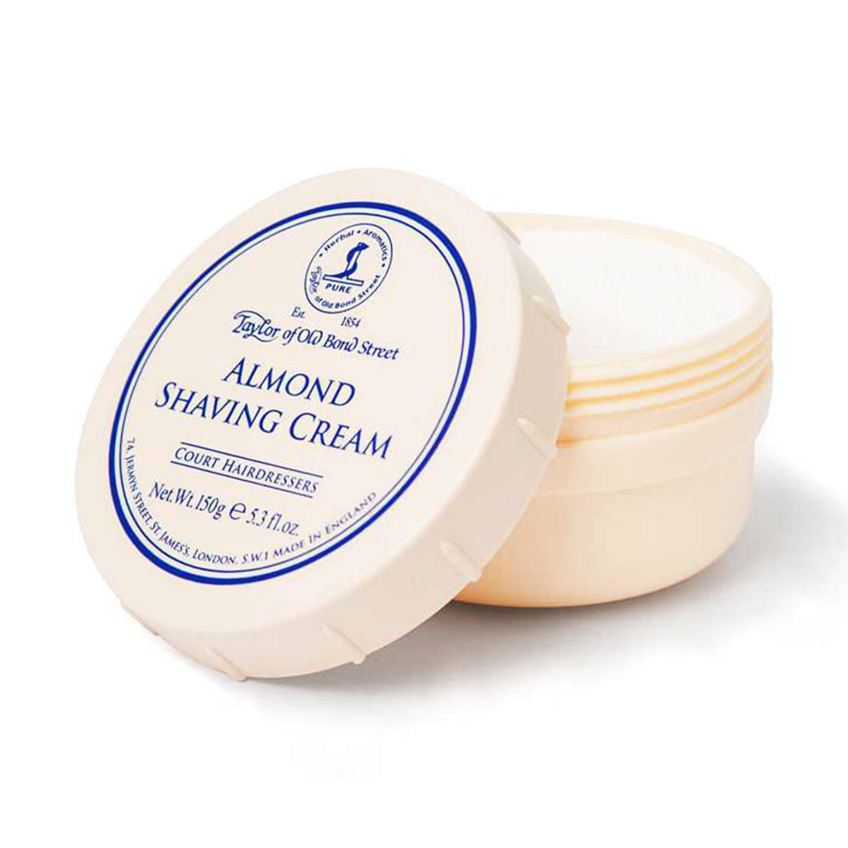 Cream-colored ceramic bowl containing almond shaving cream with blue-bordered label and removable lid.