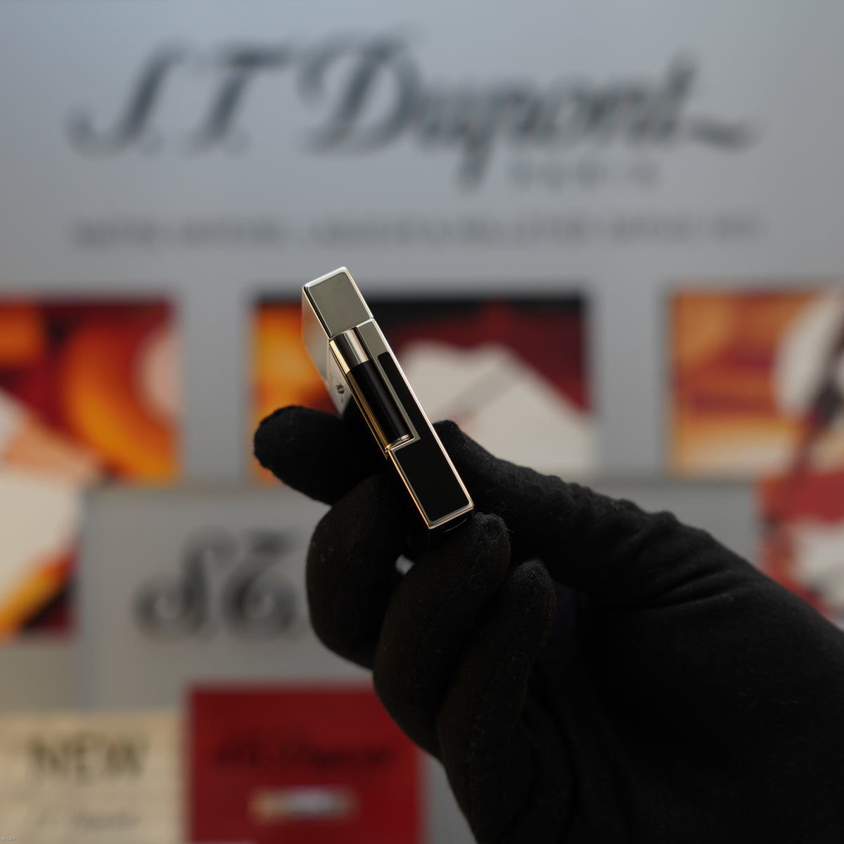 S.T. Dupont Ligne 2 lighter with black lacquer body and platinum-tone metal trim held in gloved hand.
