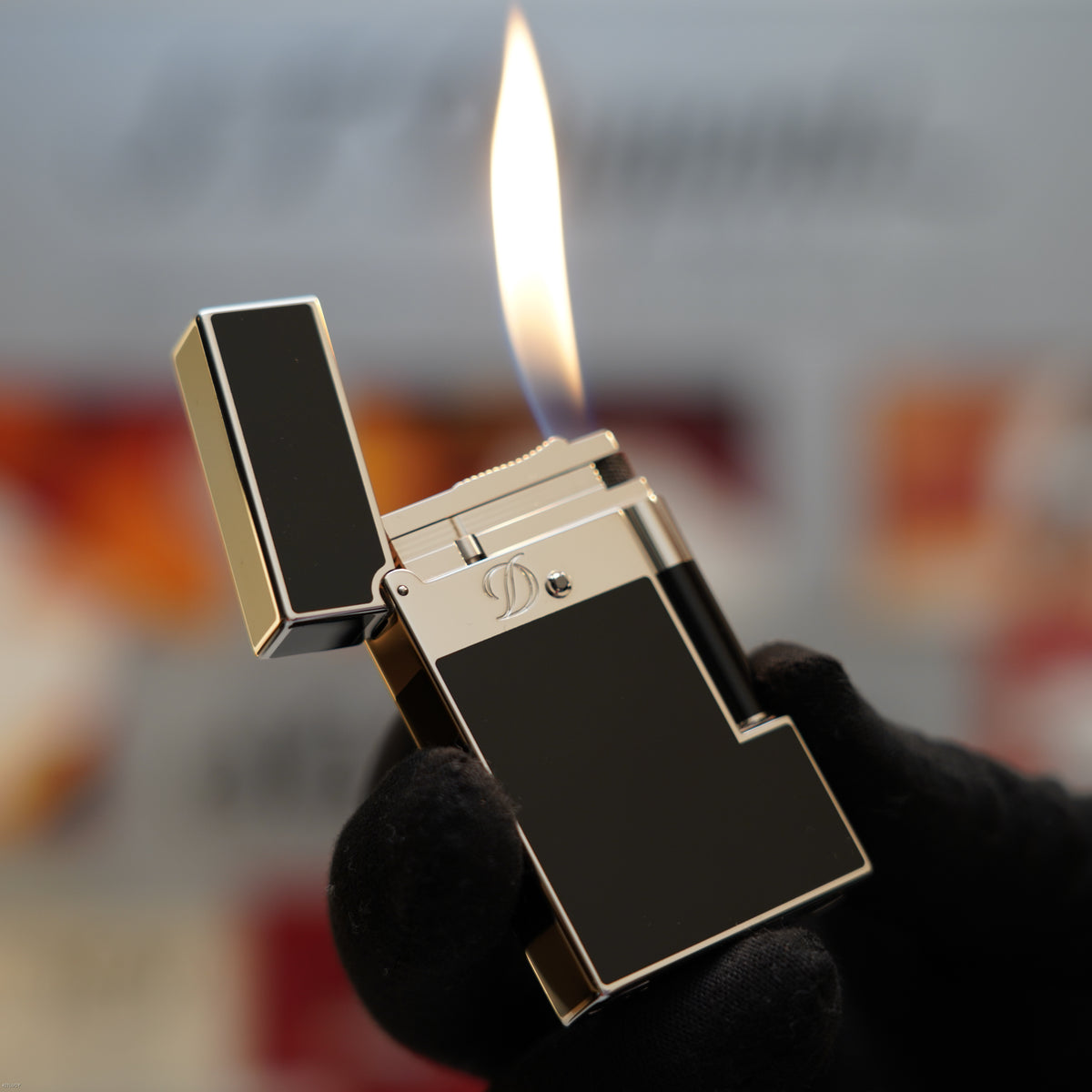 S.T. Dupont Ligne 2 lighter with black lacquer body, platinum trim, and lit flame held in hand.
