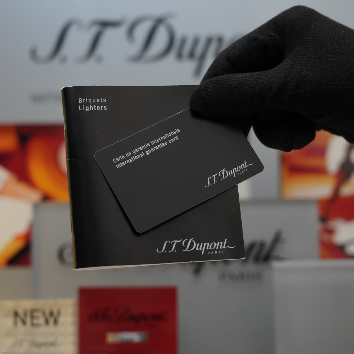 S.T. Dupont documentation and warranty card held in black gloved hand with branded packaging visible.