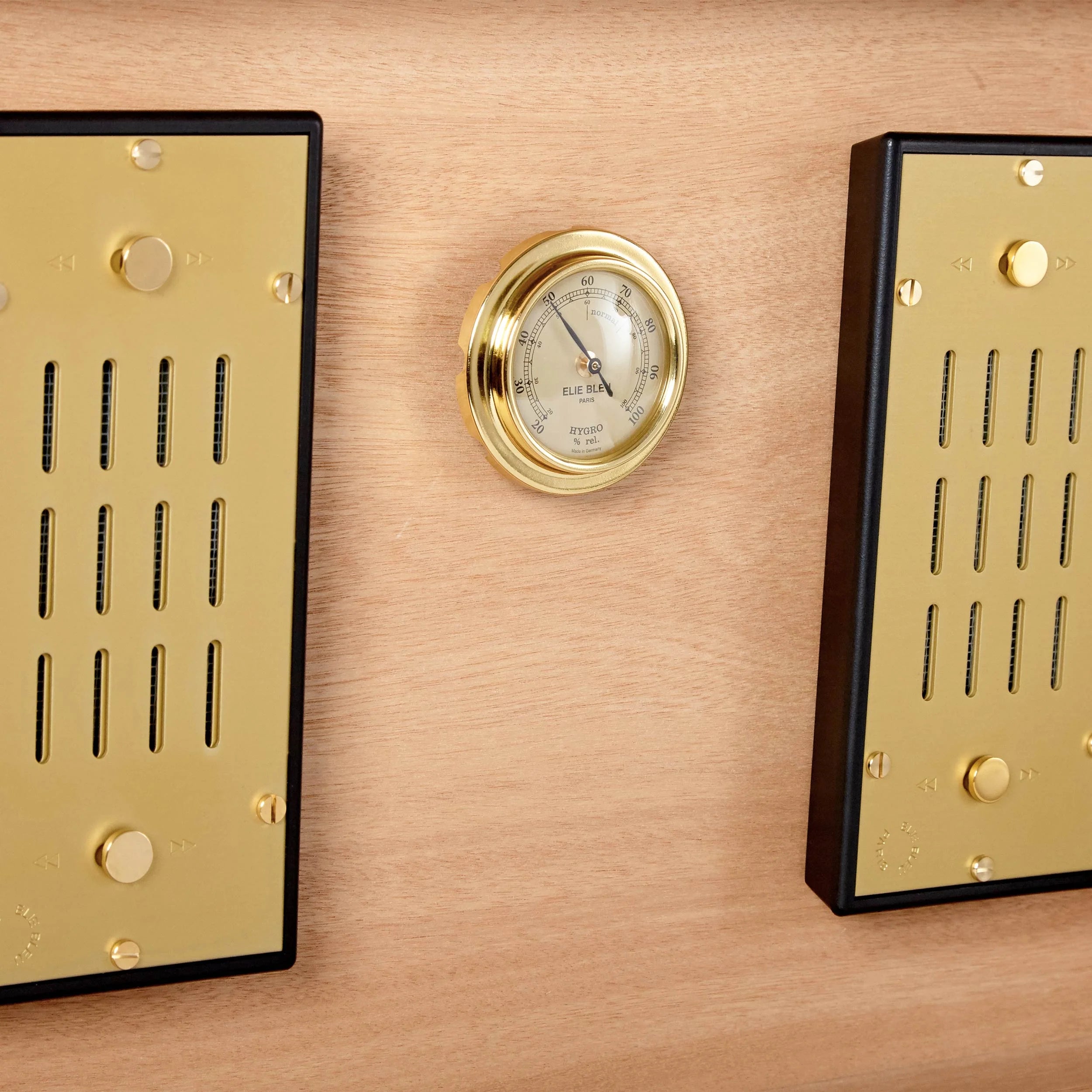 Two Elie Bleu Amboyna Burl "Classic" humidors displaying a cigar collection on a wooden wall.