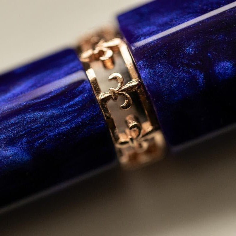 Close-up of a Visconti Medici Viola Violet - Fountain Pen (18kt Gold Nib) with a gold-colored band around its cap, featuring intricate designs.