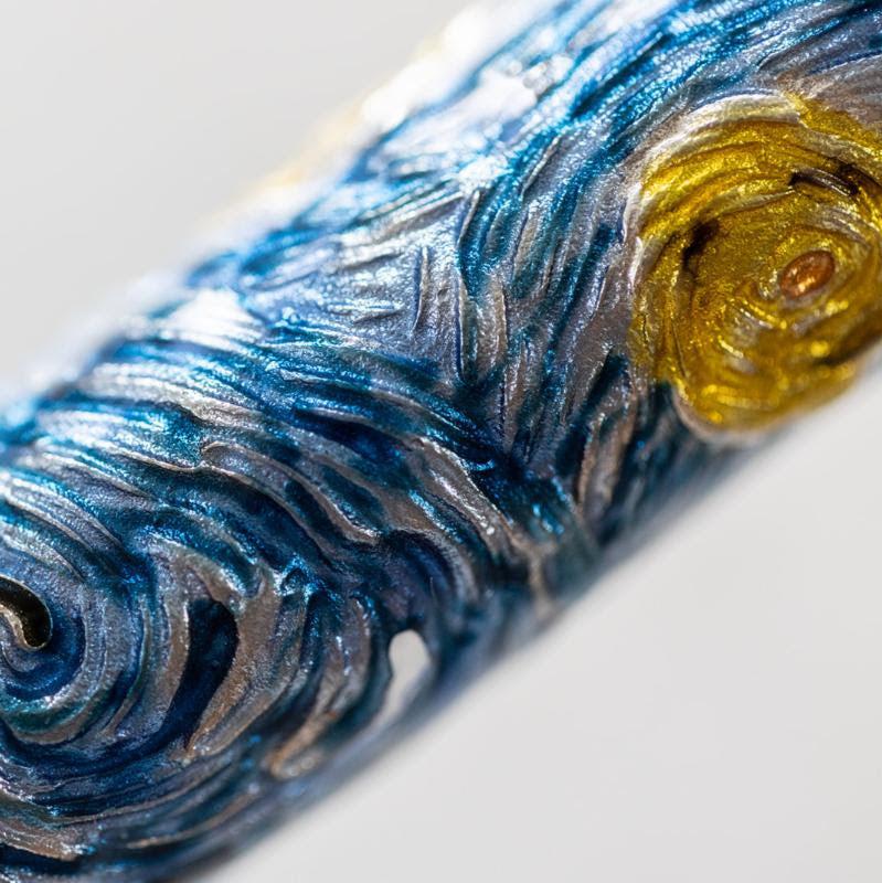 Close-up image of a limited edition Visconti Van Gogh Dreaming Starry Night Fountain Pen with intricate, swirling designs in blue and yellow, resembling a textured painting.