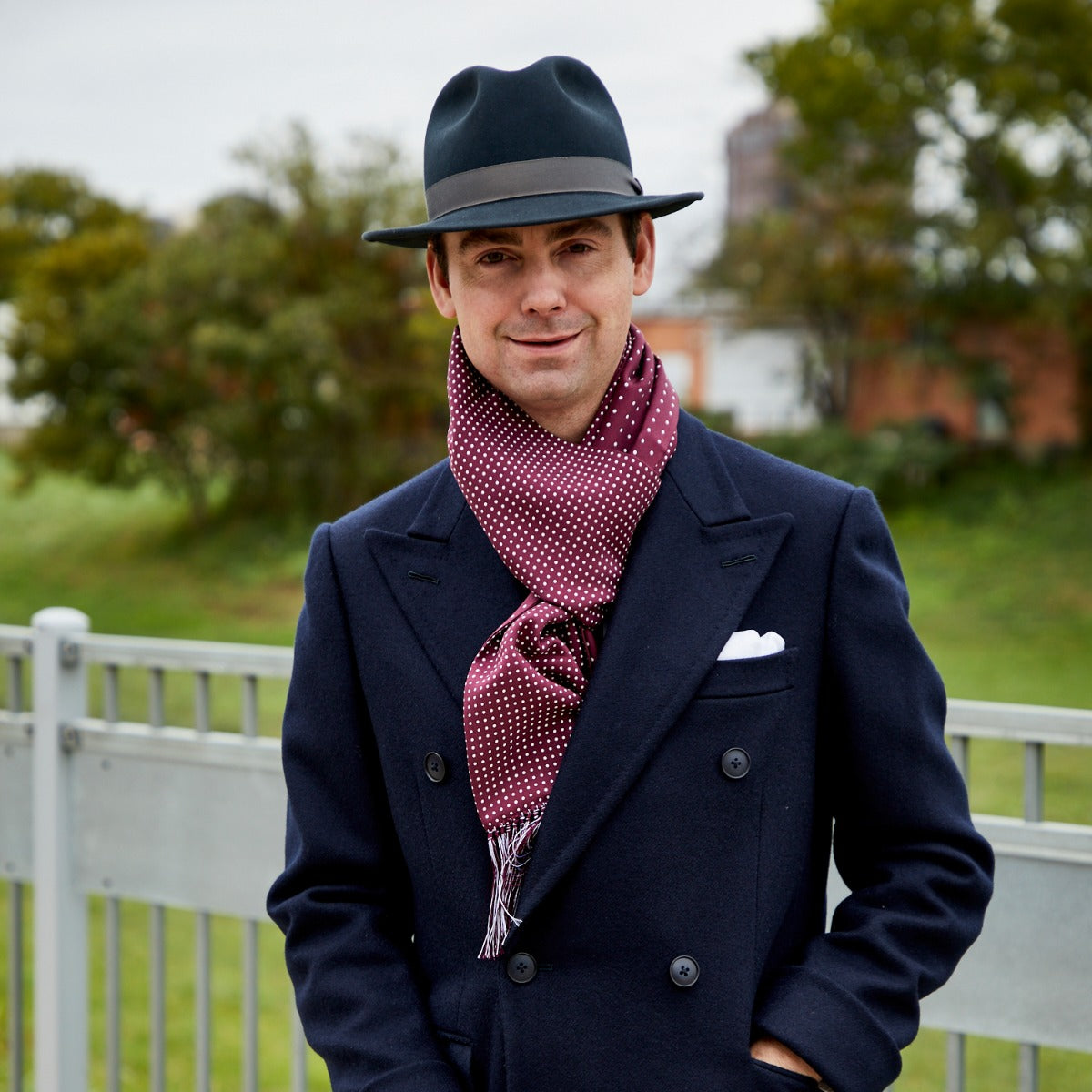 A man wearing a Sovereign Grade Burgundy London Dot 36oz Reversible Printed Silk Scarf from KirbyAllison.com.