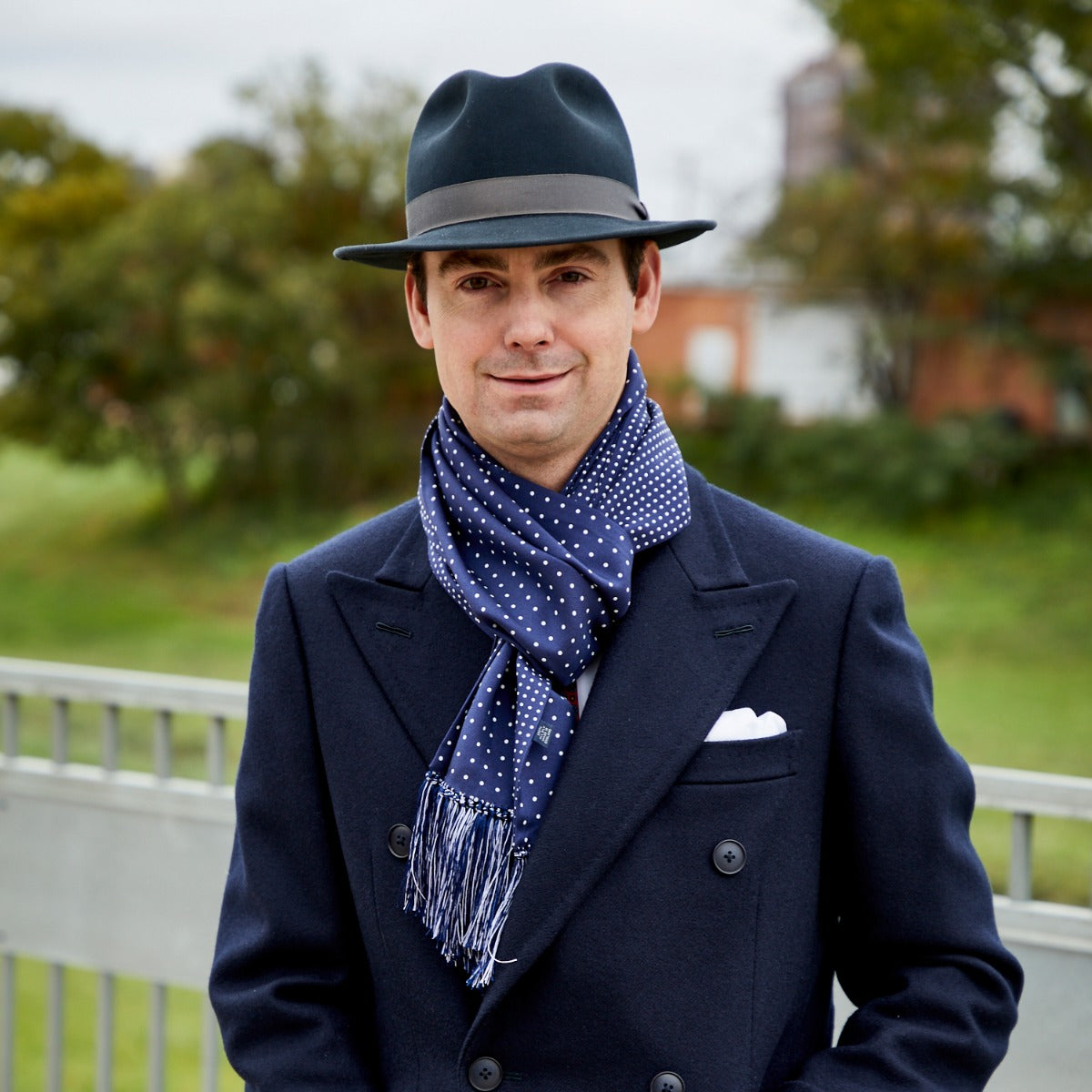 A man wearing a Sovereign Grade Navy London Dot 36oz Reversible Printed Silk Scarf from KirbyAllison.com.