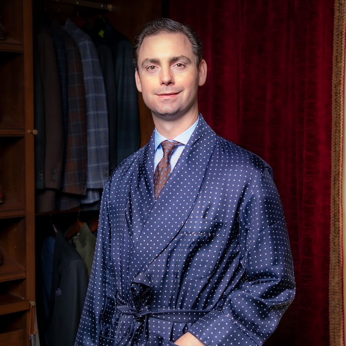 A man in a Sovereign Grade Navy London Dot Dressing Gown by KirbyAllison.com standing in a closet.