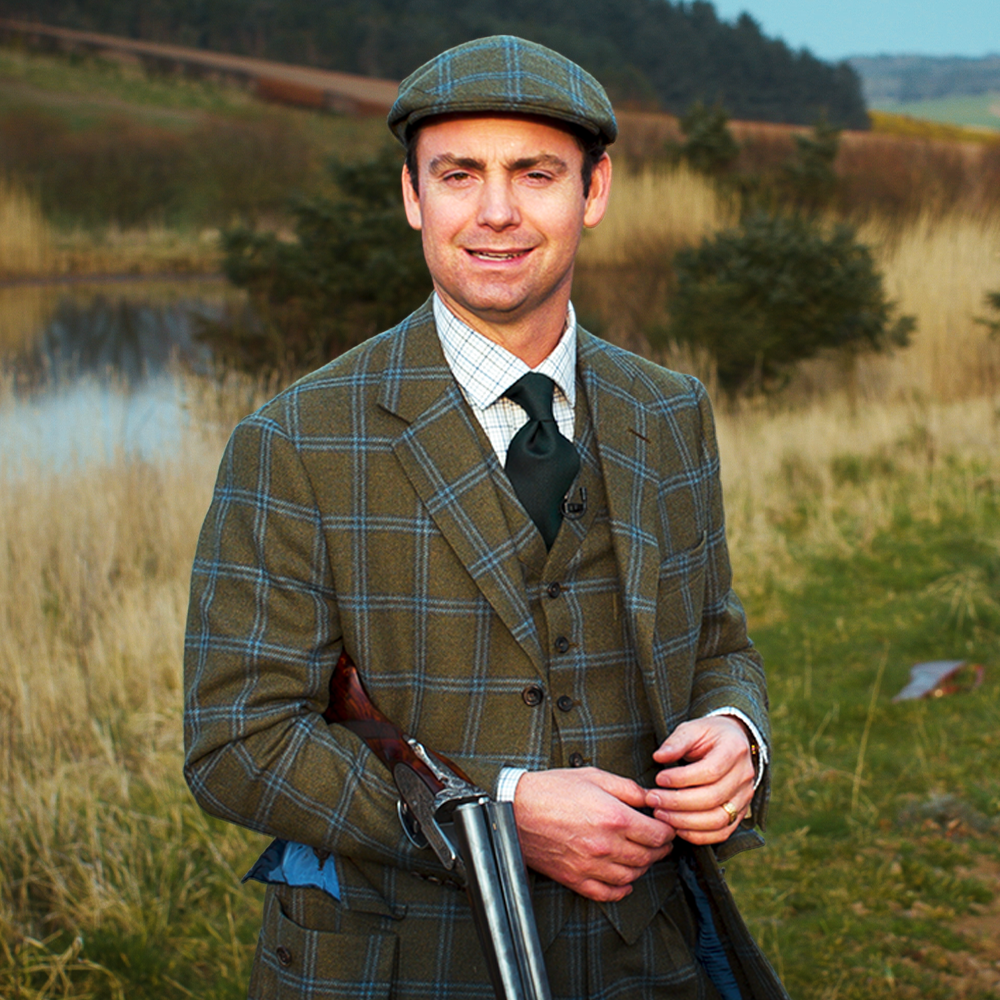 A man in a Lovat Mill suit holding a gun visits Scotland.