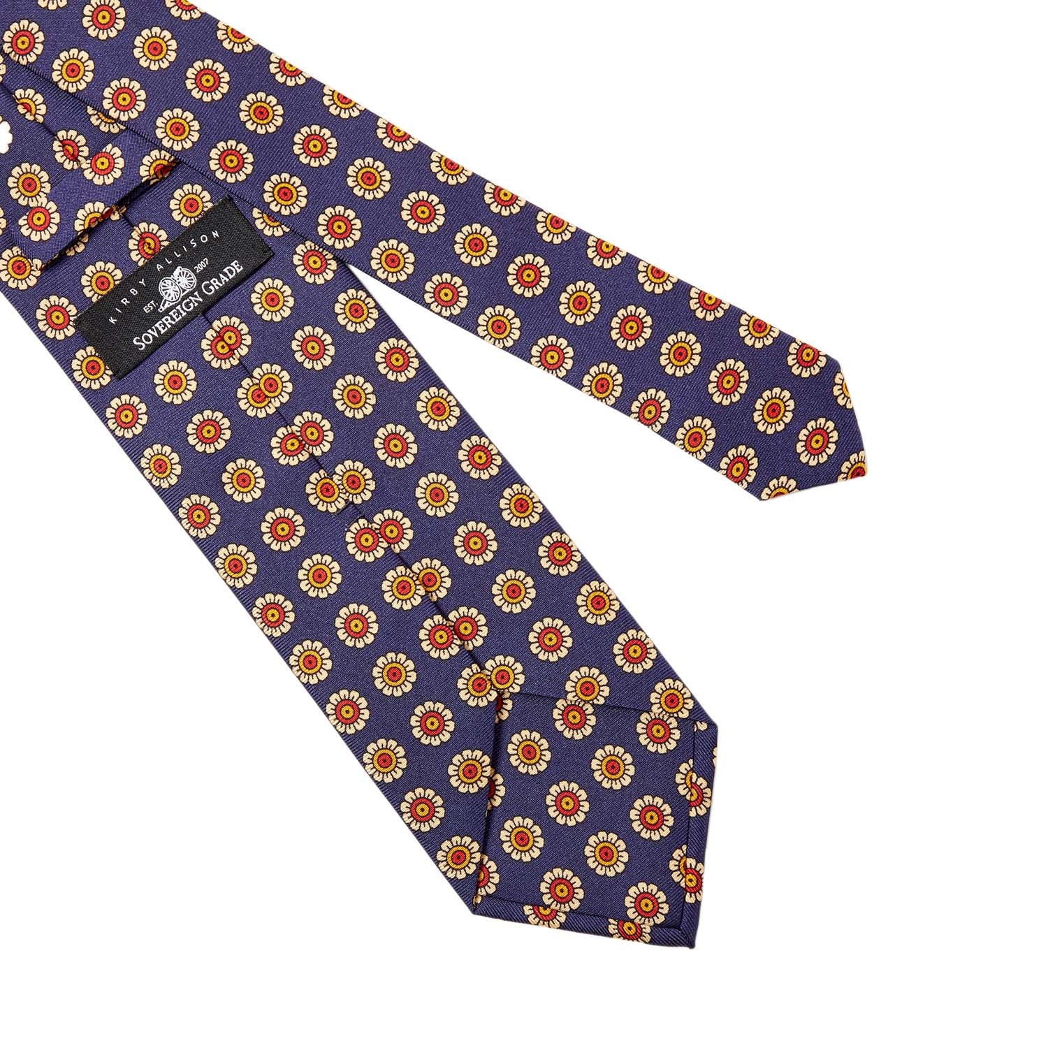 A Sovereign Grade Navy Daisy Spring Madder Buff Tie (150x8.5 cm) from KirbyAllison.com, made of 100% English silk, with orange and yellow flowers on it.